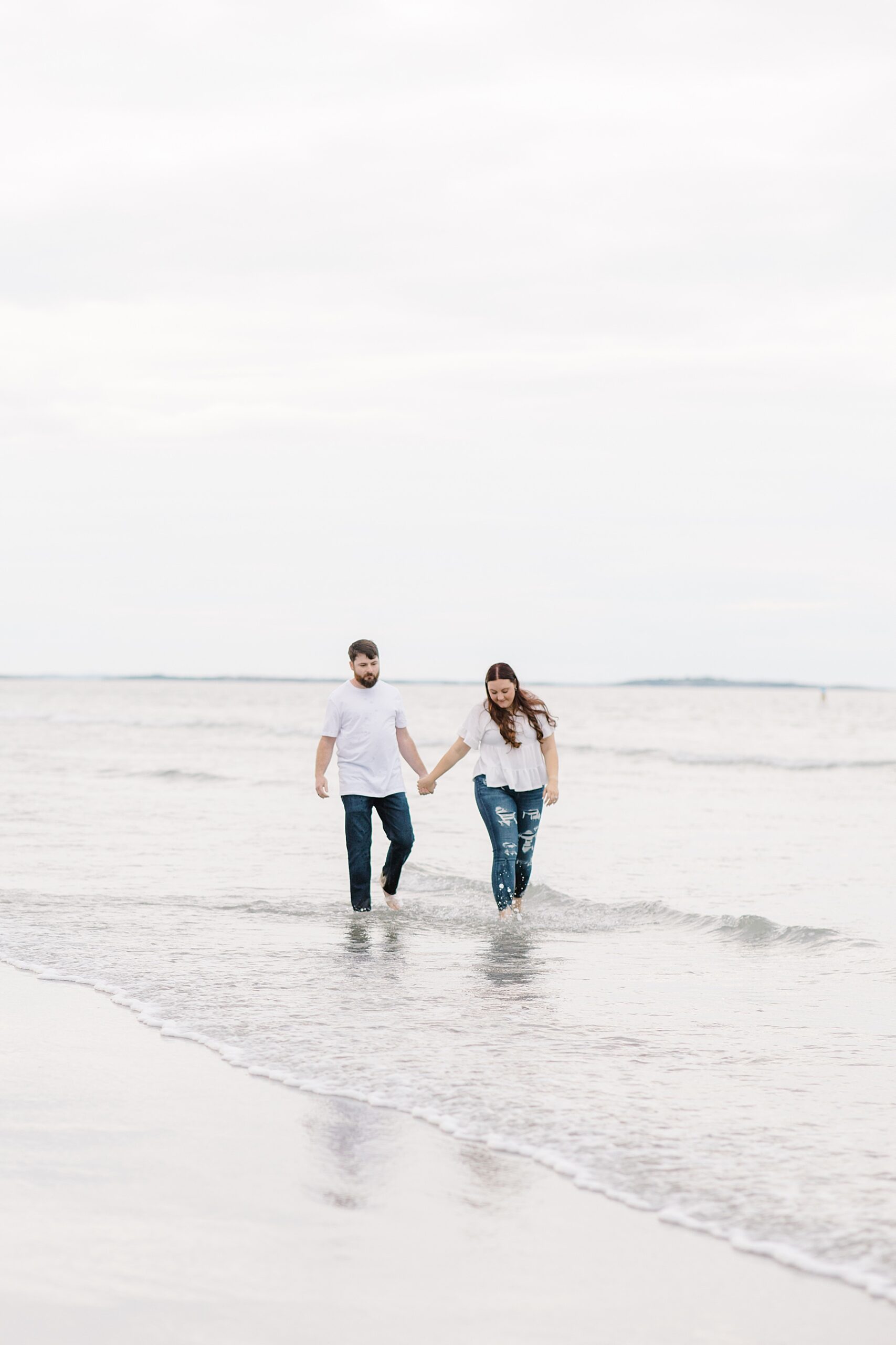 couple splash in the water during beach engagement 