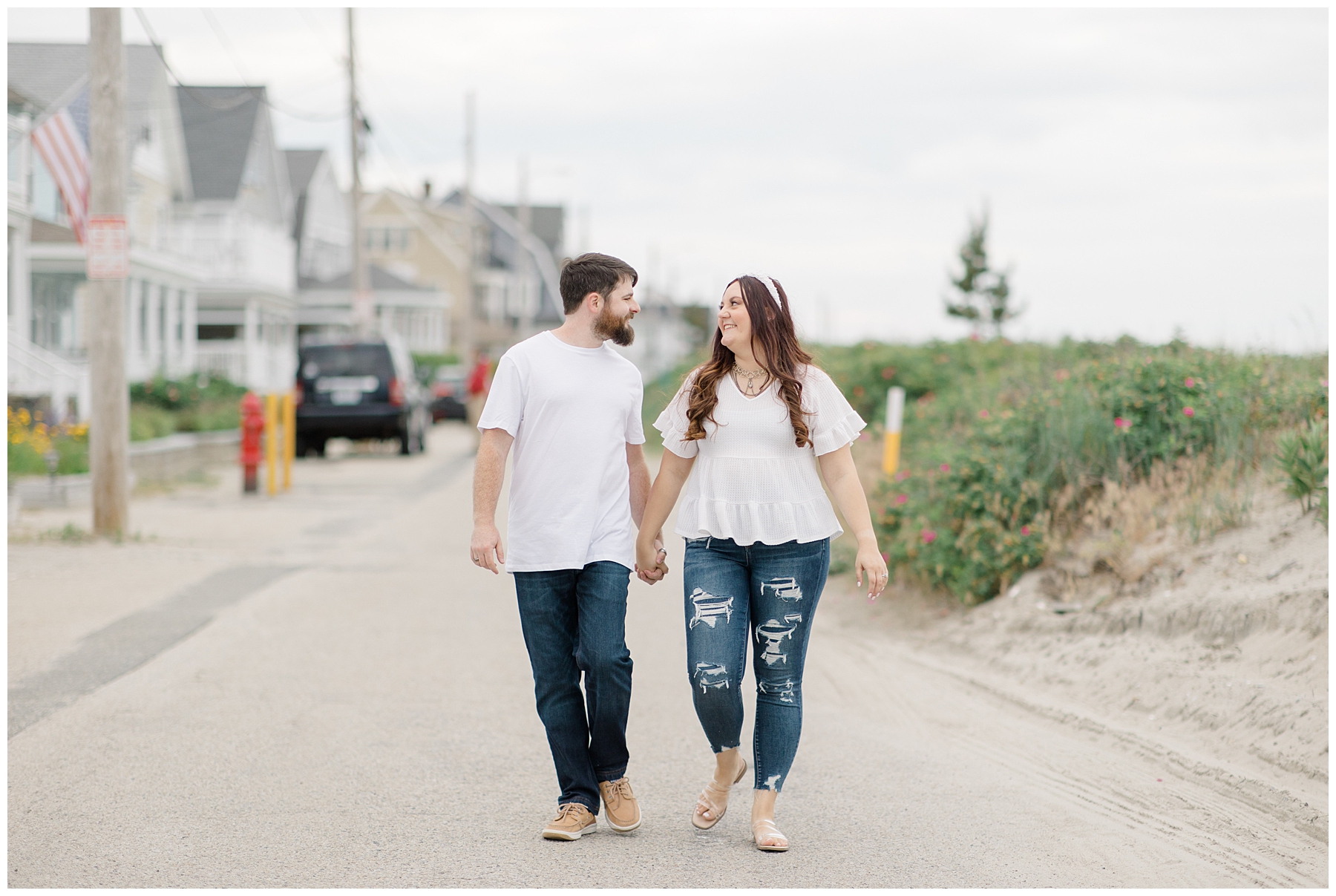 couple walk along street by Nantasket Beach during engagement portaits 