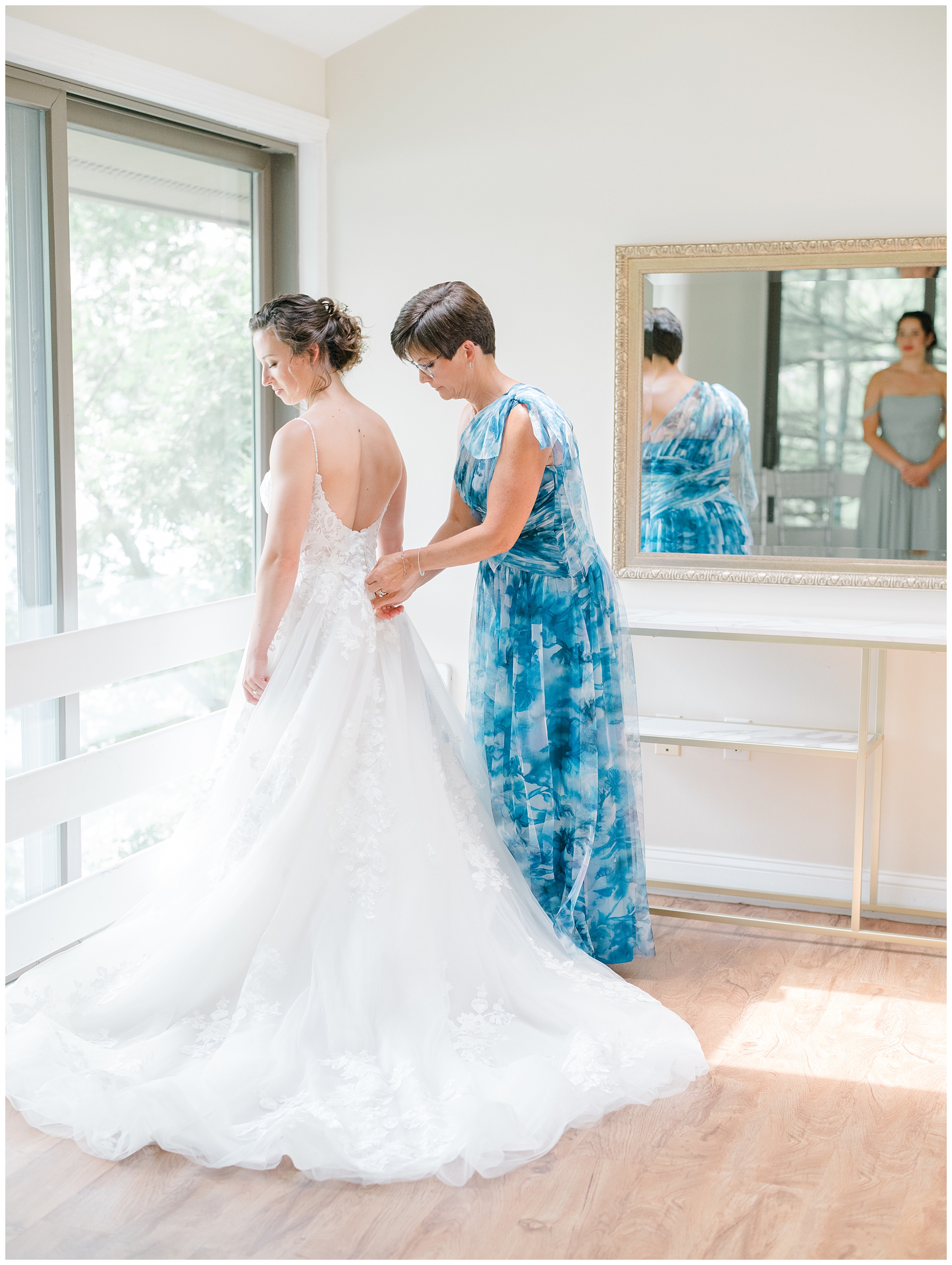 bride getting into wedding dress with mom 