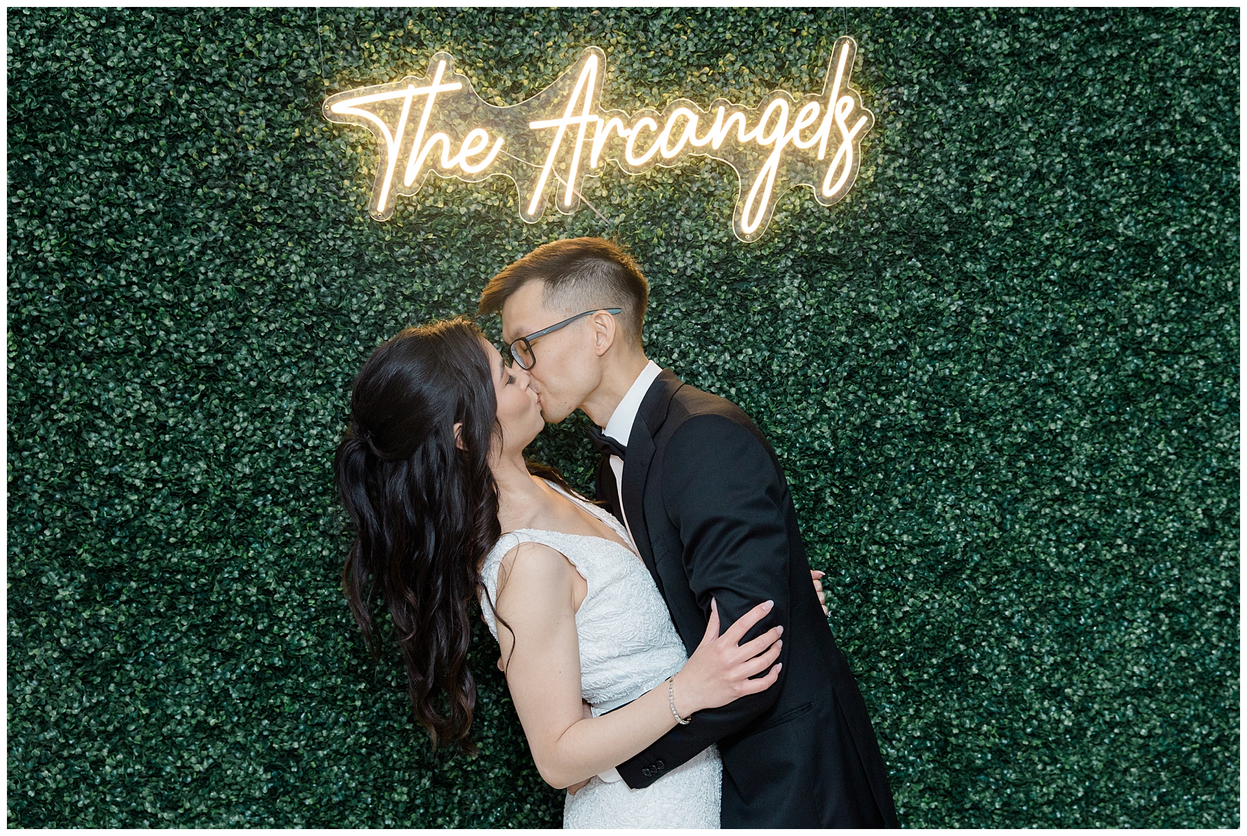 newlyweds kiss under light up sign of last name