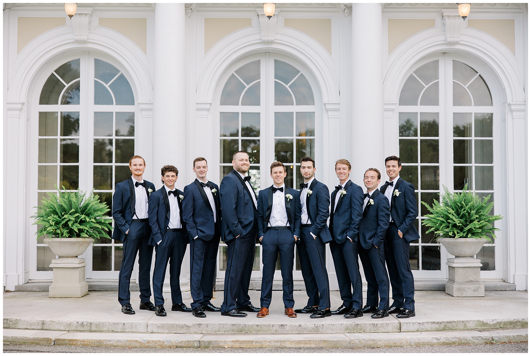 groomsmen and groom stand on patio of Tupper Manor