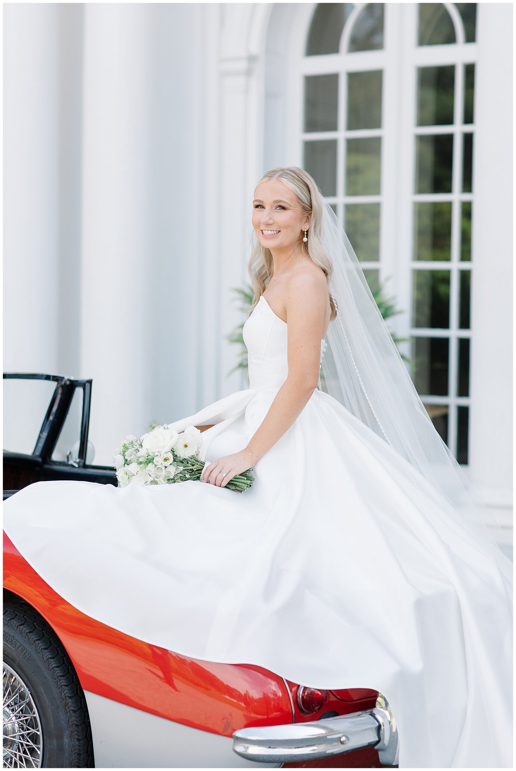 bride sits on red vintage car