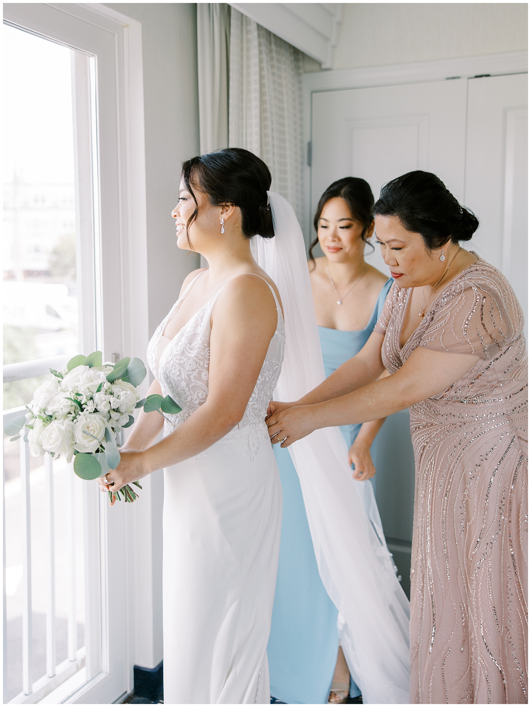 bride getting into wedding dress with mom