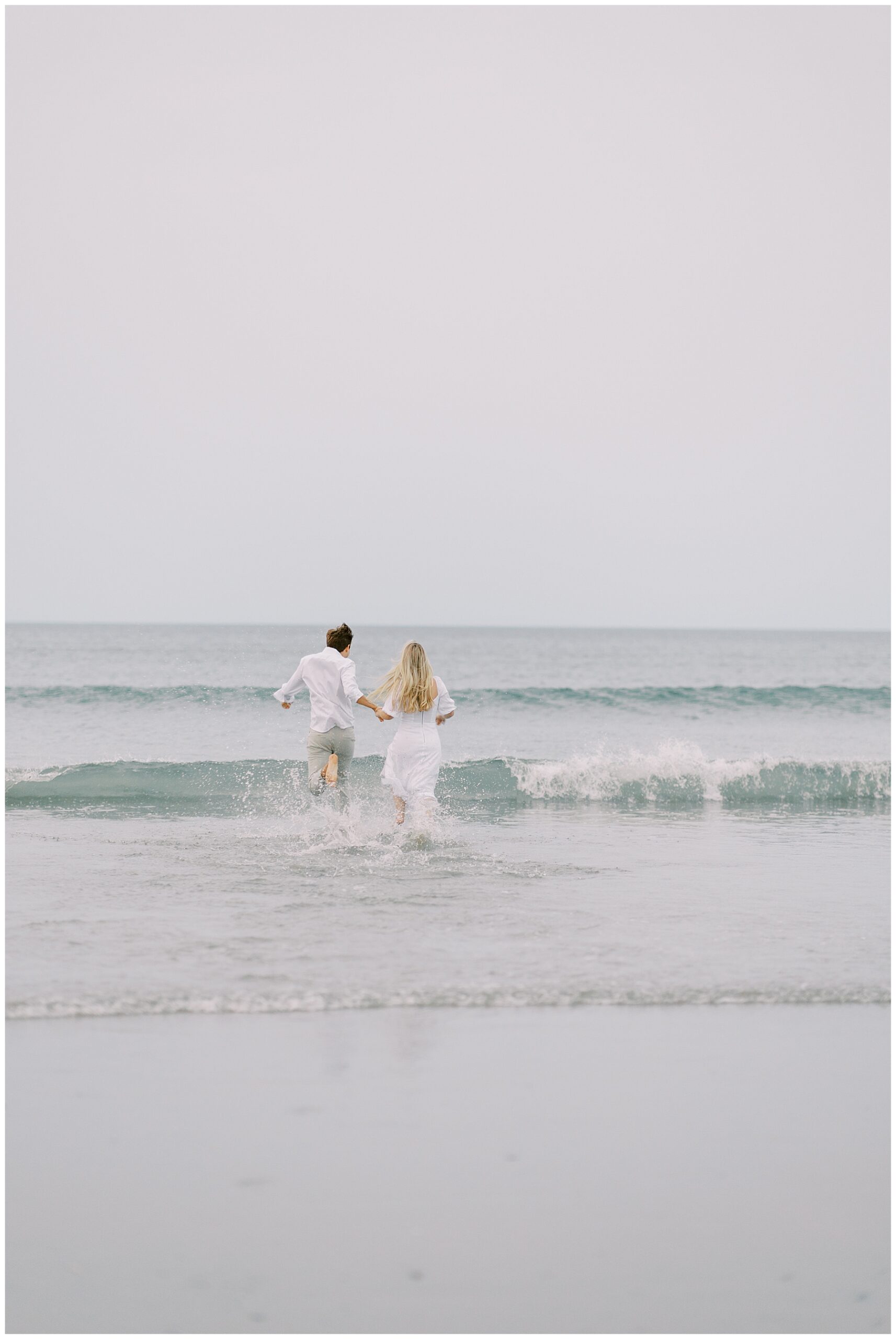 Candid Engagement photos of couple running into the water at Nantasket Beach