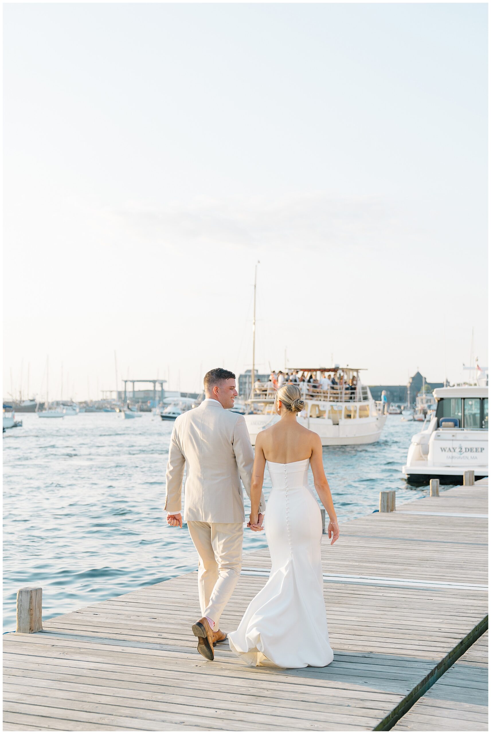 newlyweds walk along the dock at Newport