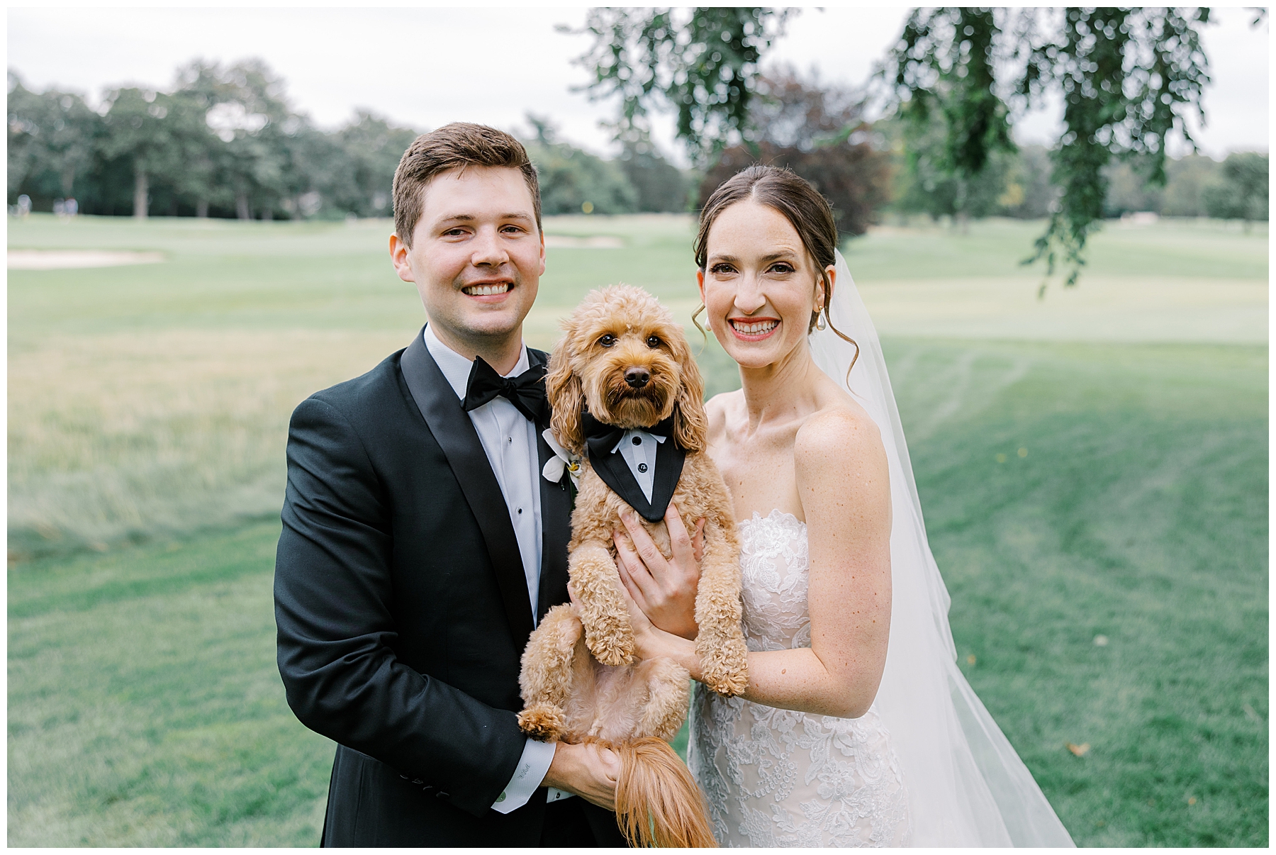bride and groom hold their dog for wedding portraits 