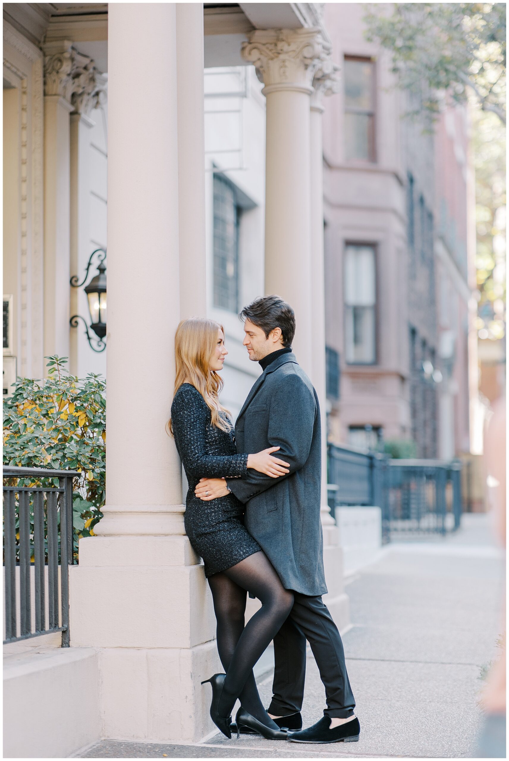 Romantic engagement portraits of couple leaning against classic building
