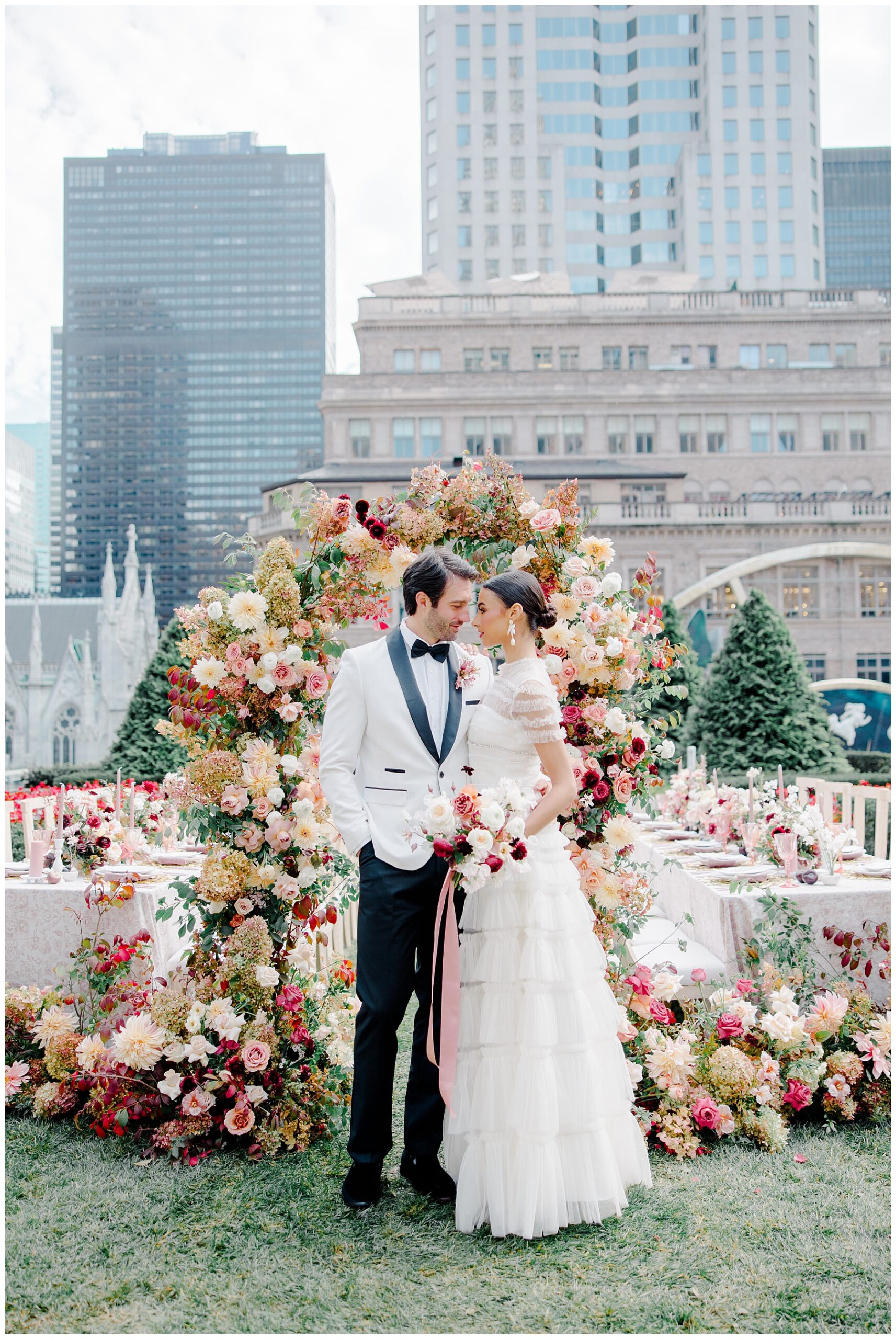 Newlyweds in front of floral arch at rooftop wedding reception