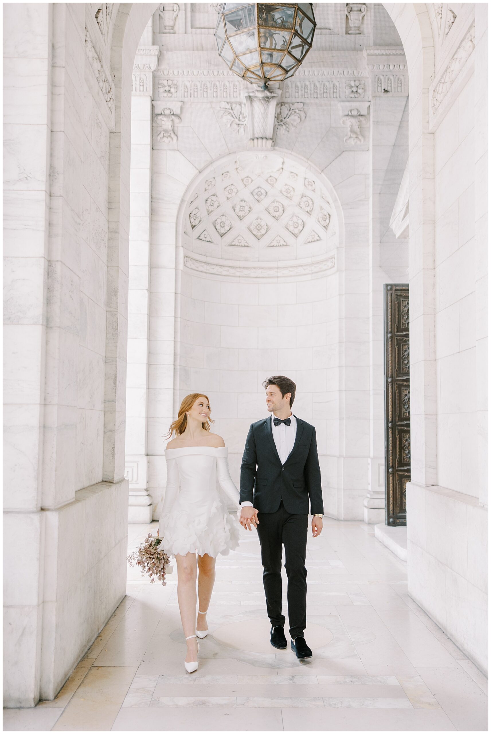 bride and groom walk through the New York Public Library