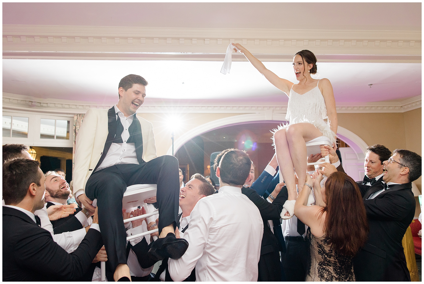 candid portraits from wedding reception as newlyweds are lifted up in chairs 