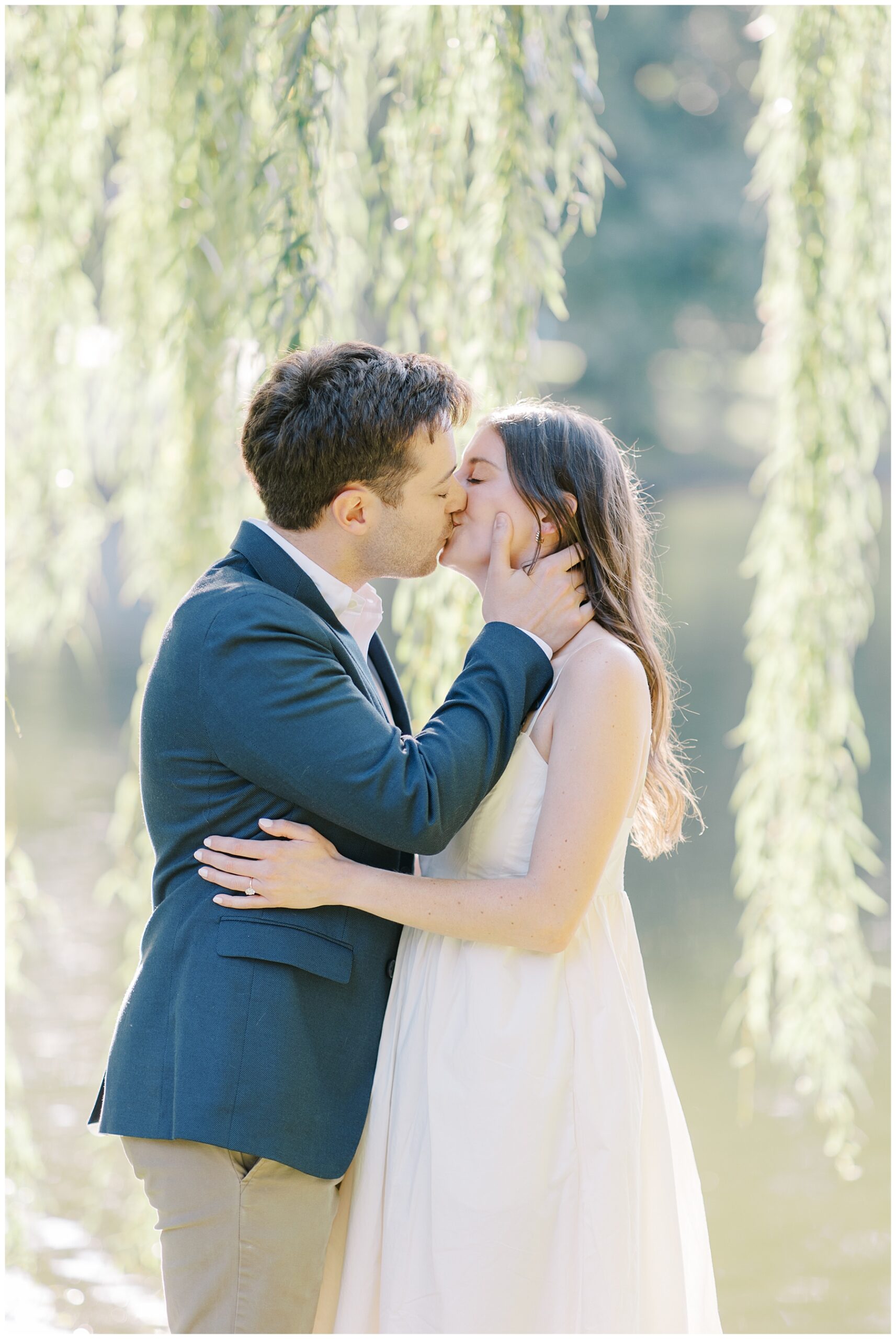 engaged couple kiss under weeping willow tree