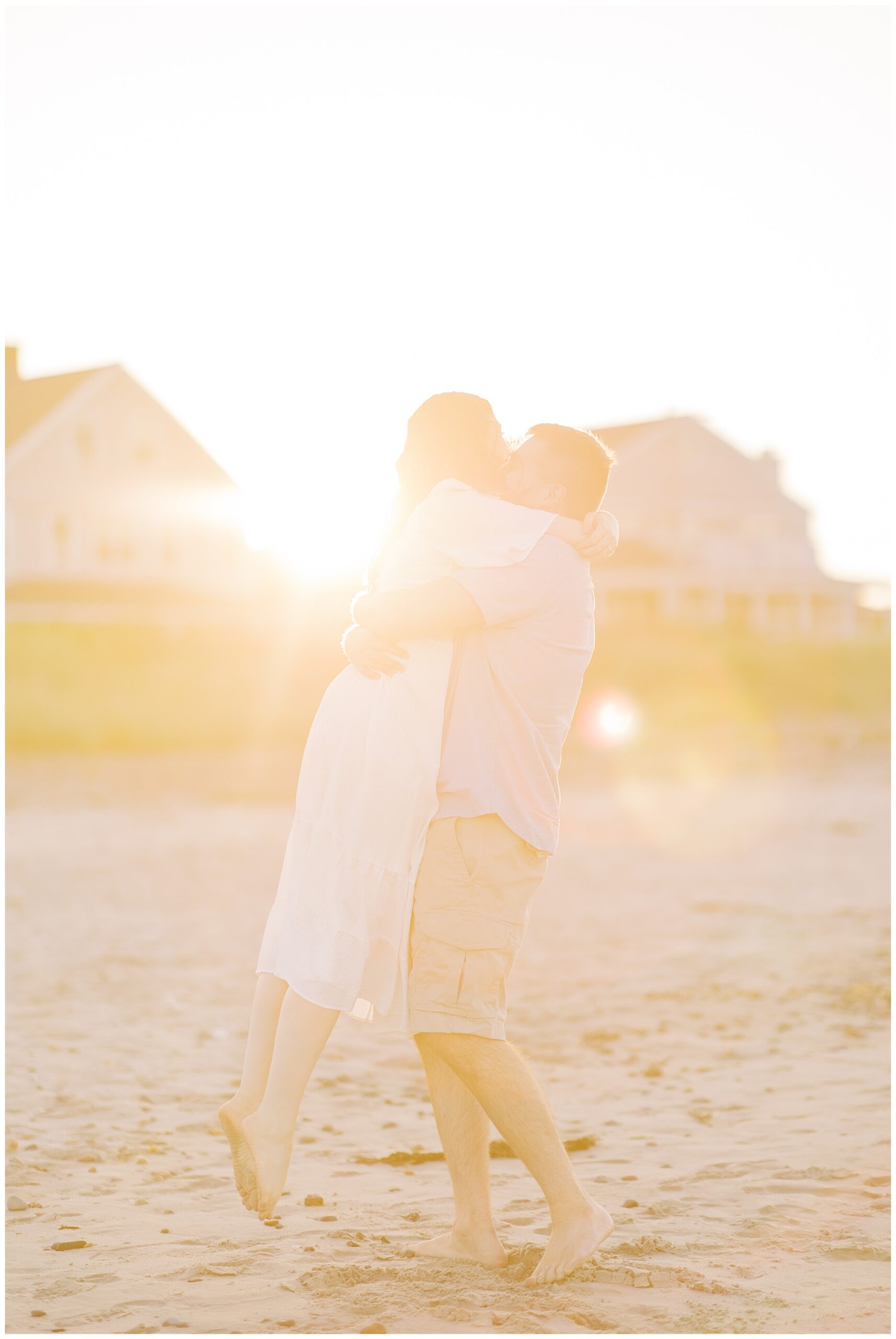 couple kiss on the beach as the sun sets behind them