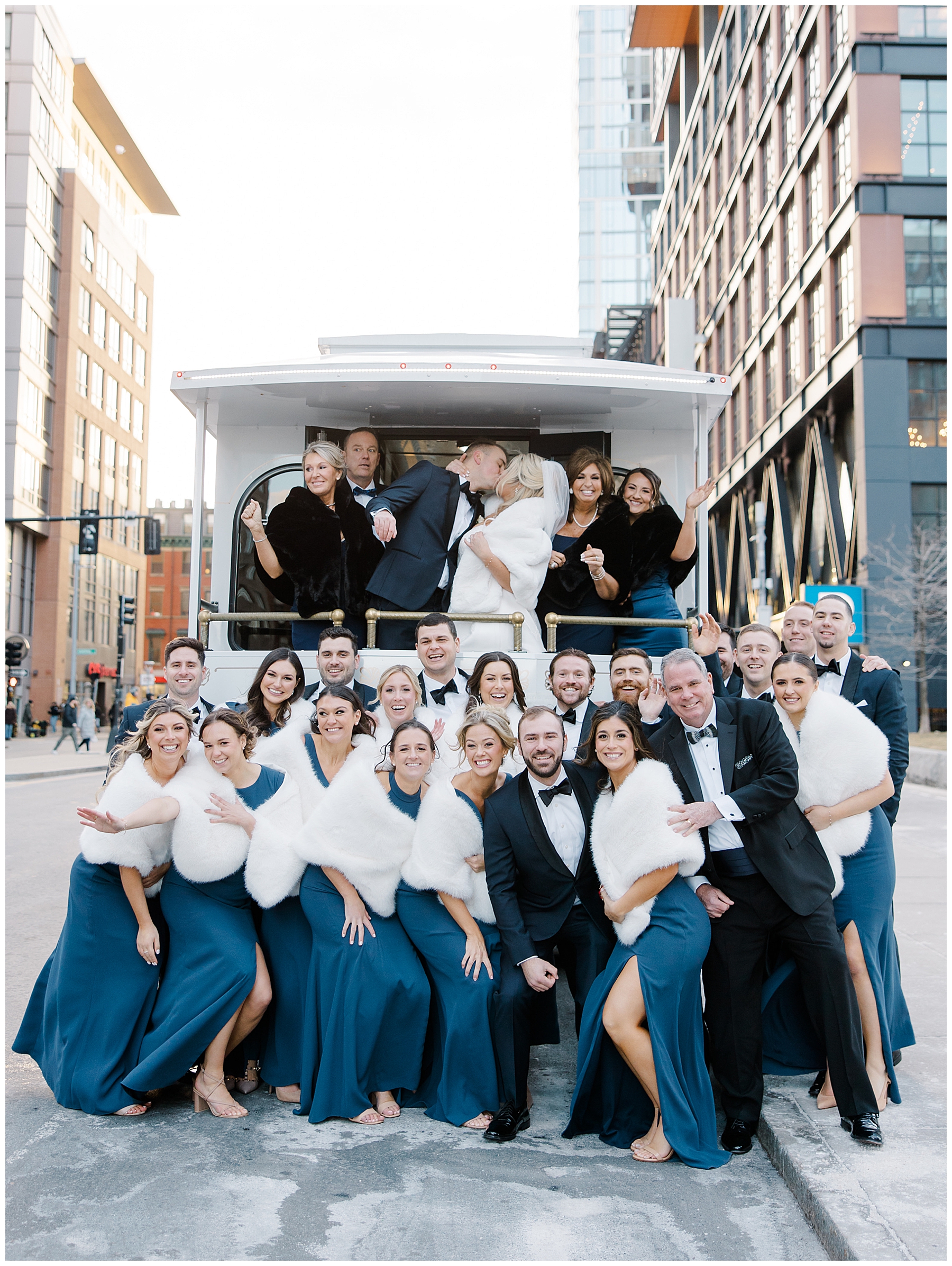 wedding party surround newlyweds as they kiss in Boston