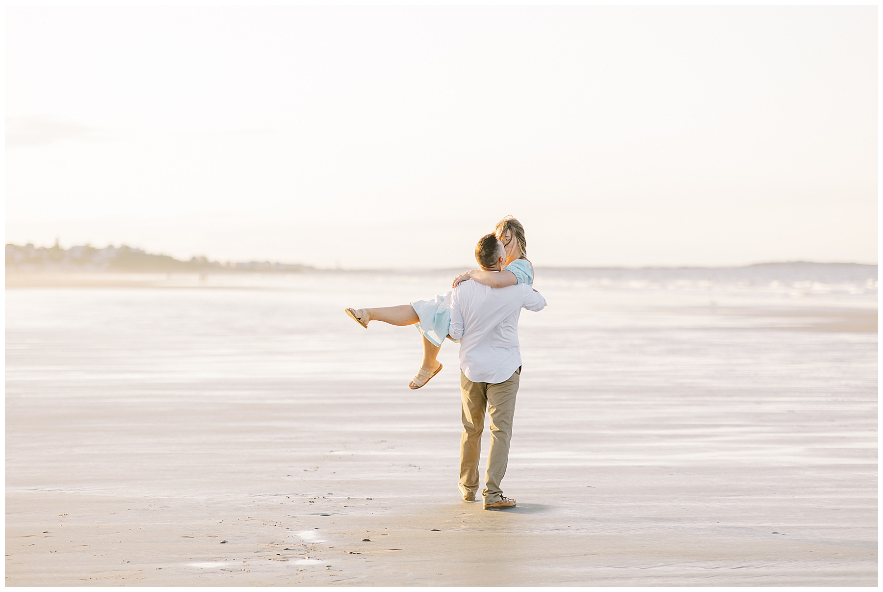 man holds fiancé on the beach 