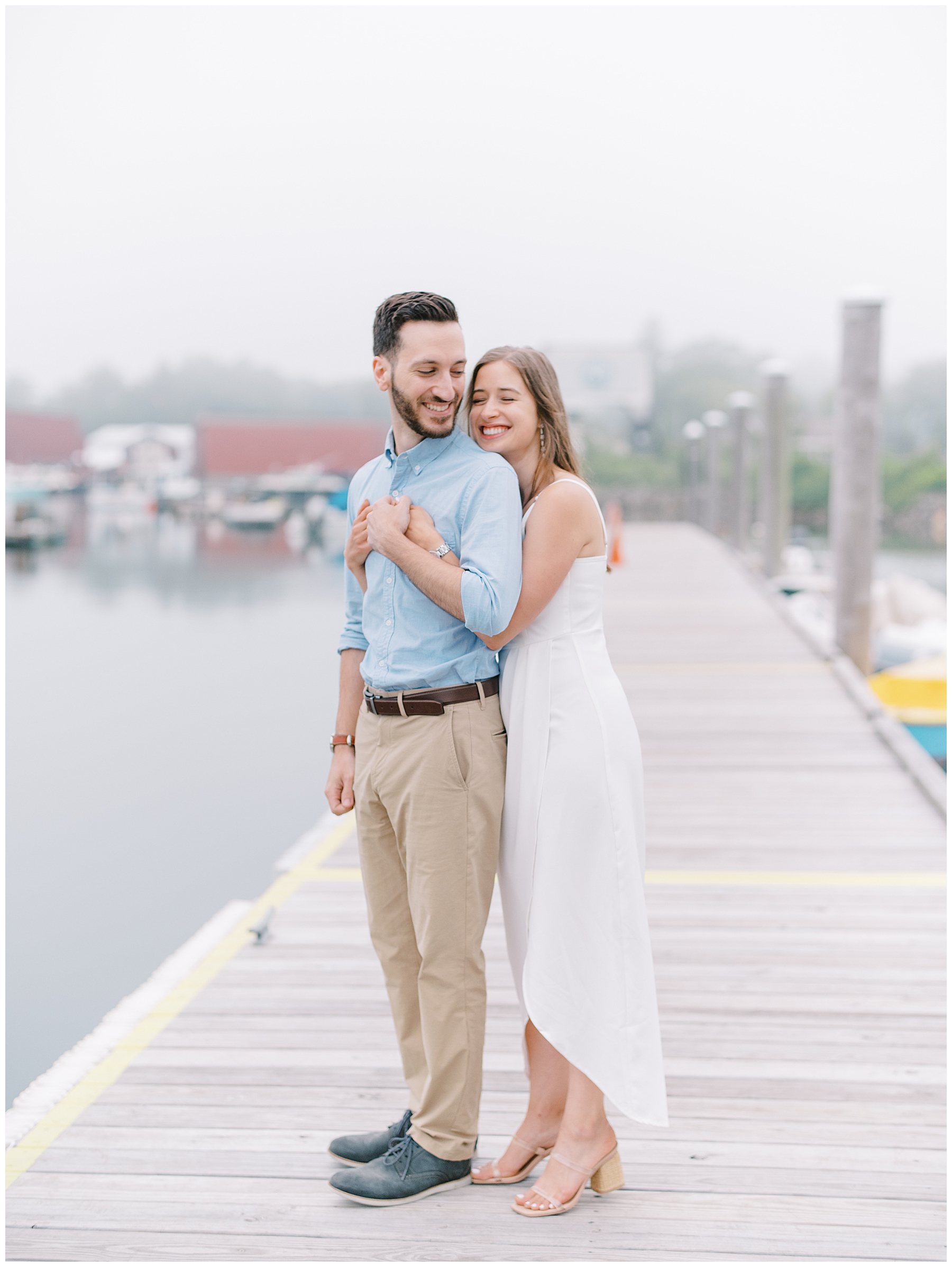 candid engagement photos of couple hugging on dock at North Shore Beach
