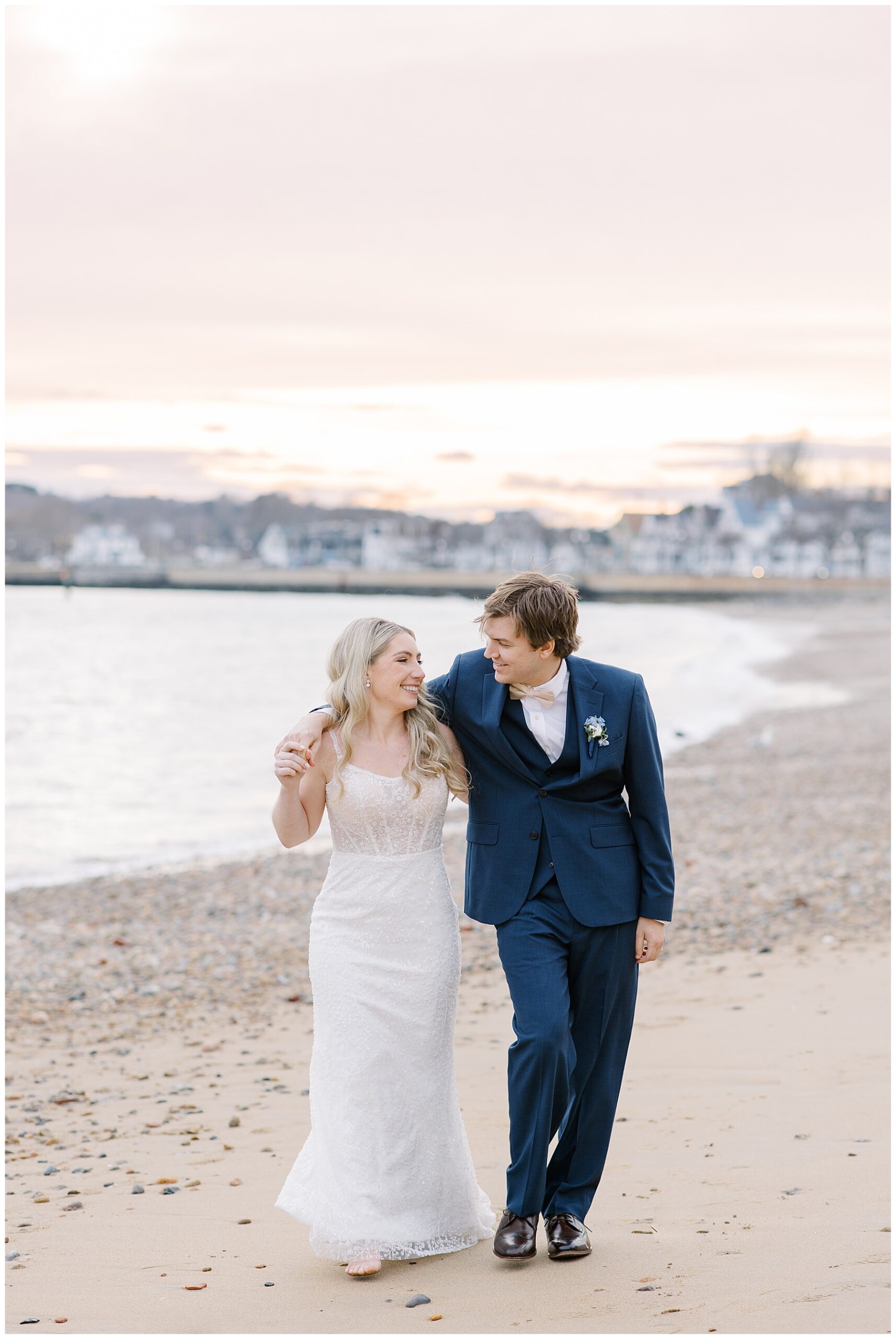 bride and groom walk together on the beach 