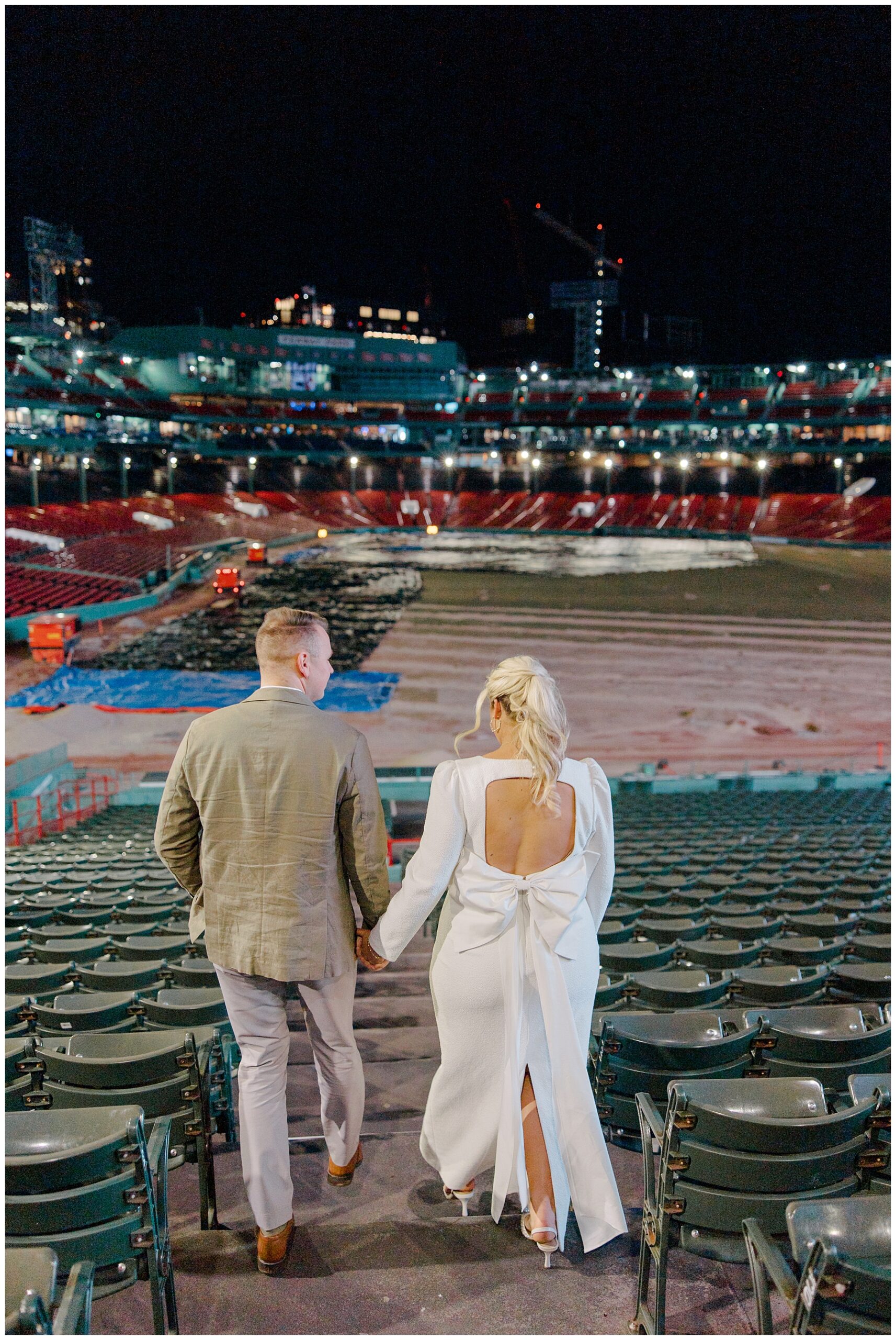 couple hold hands as they walk towards Boston Red Sox baseball stadium 