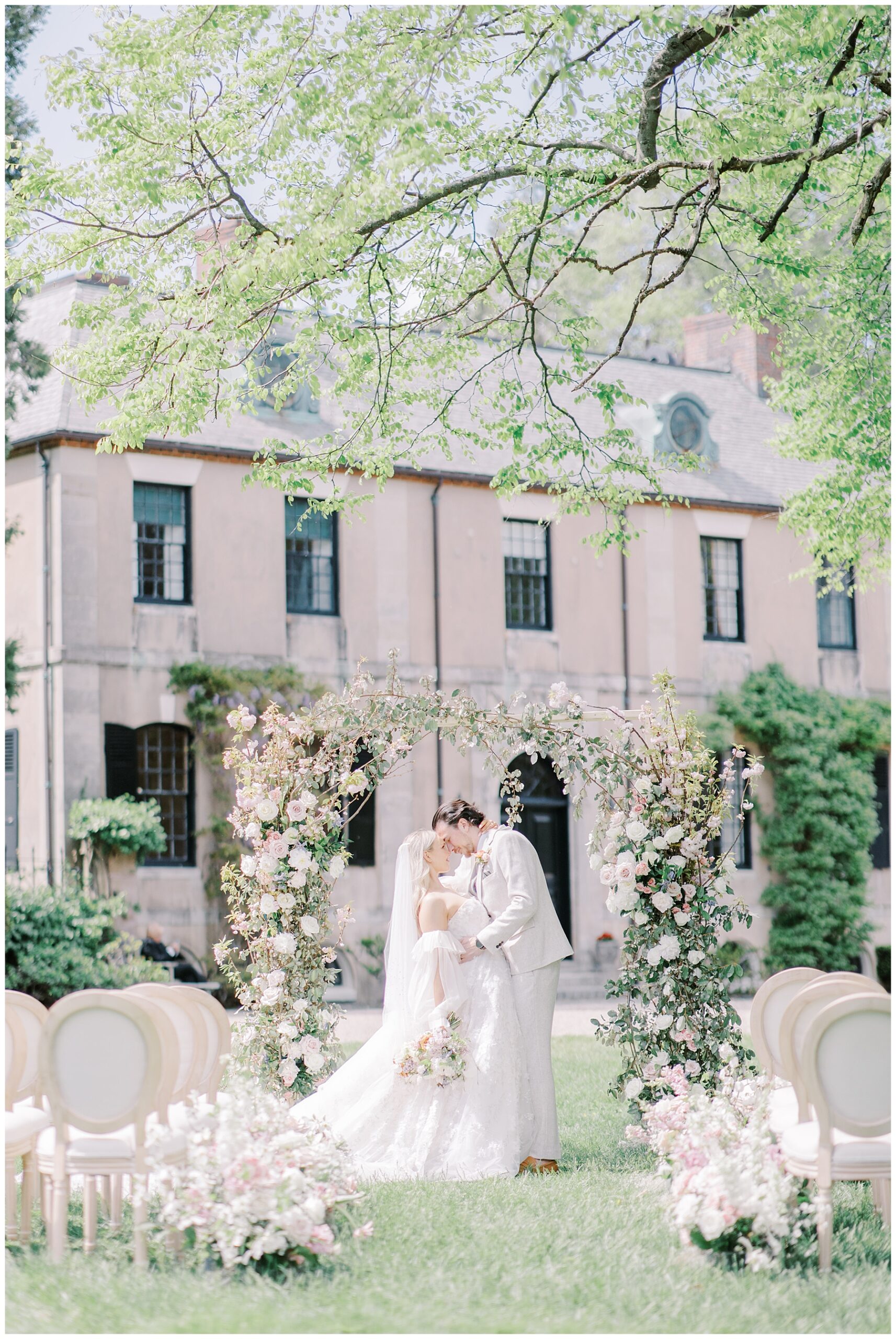 bride and groom kiss under floral wedding arch