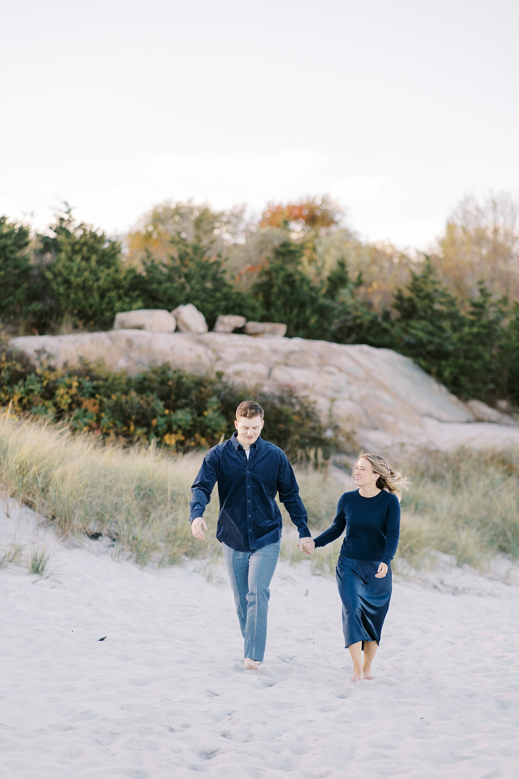 couple hold hands and walk the beach