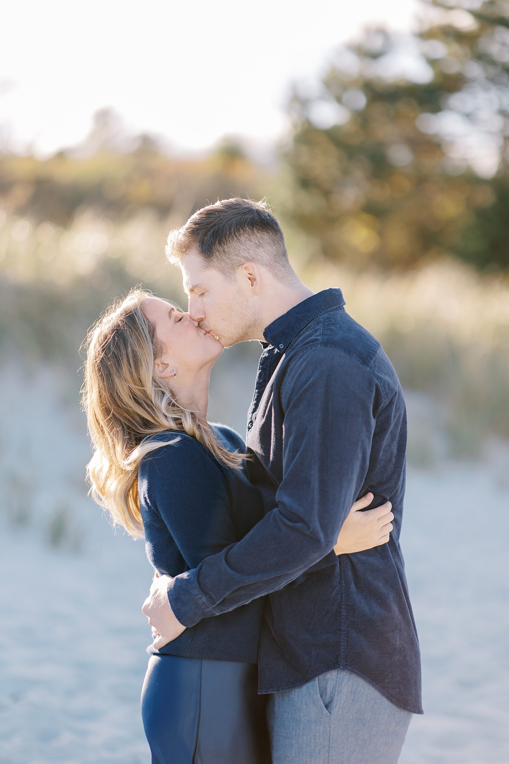 engaged couple kiss on the beach