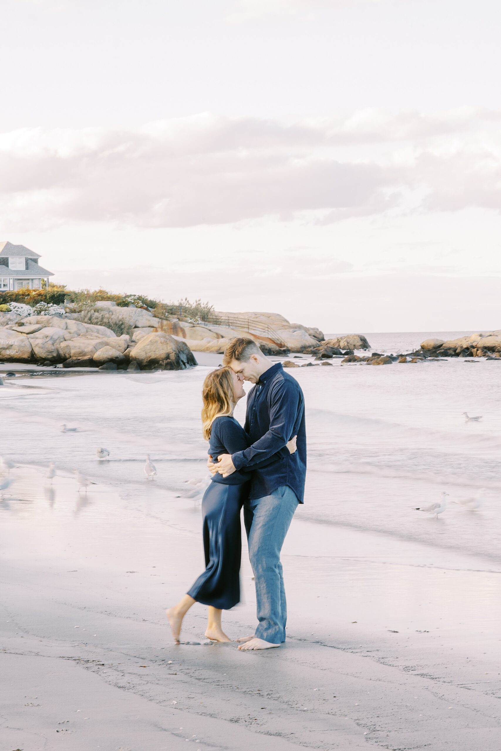 couple kiss on rocky shores of Wingaersheek Beach