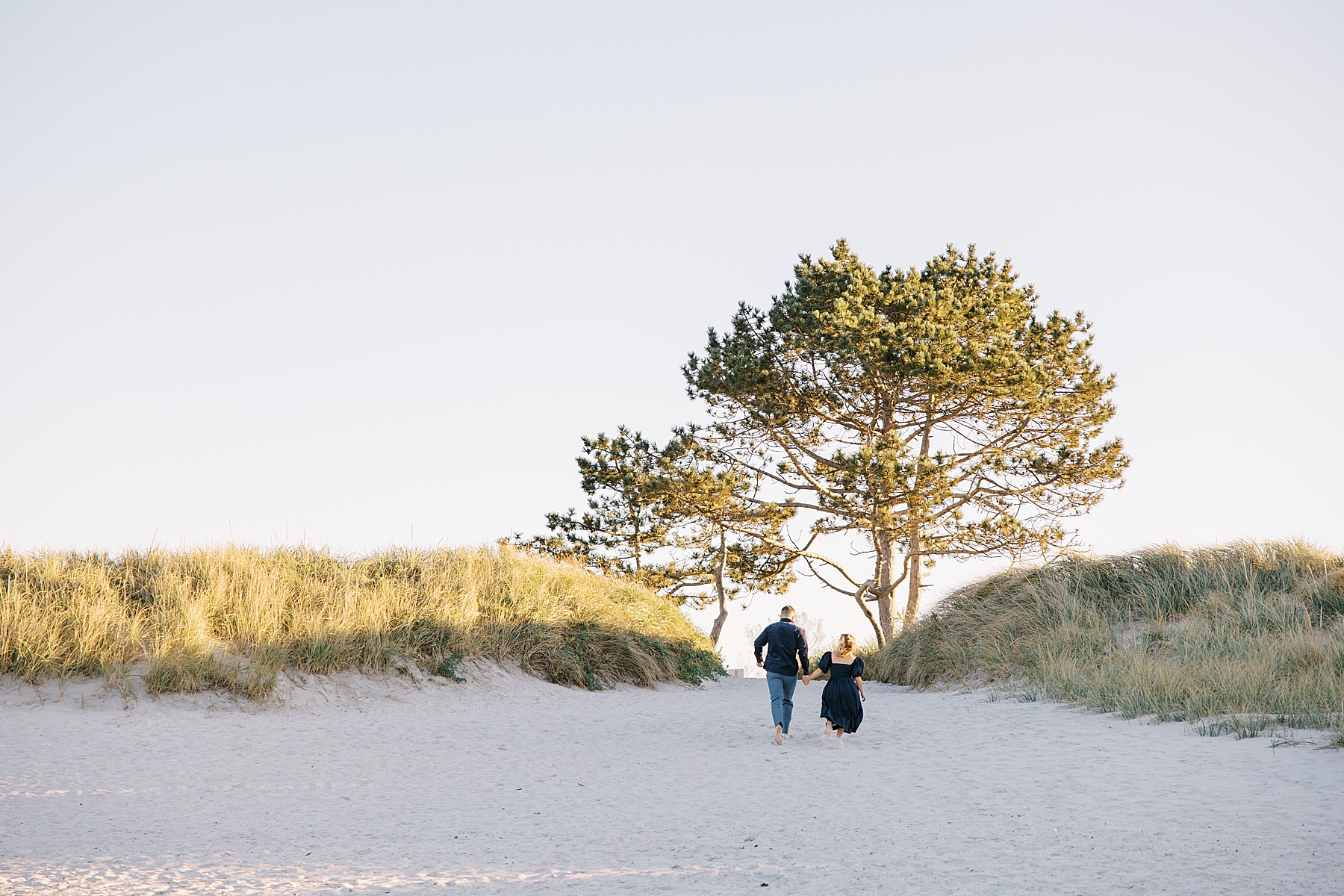 couple walk up sandy hill at the beach