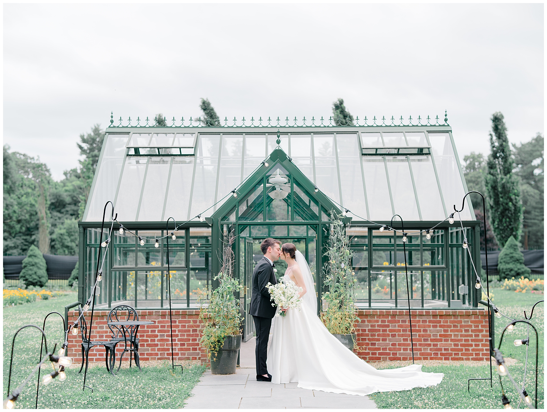 bride and groom stand in front of greenhouse