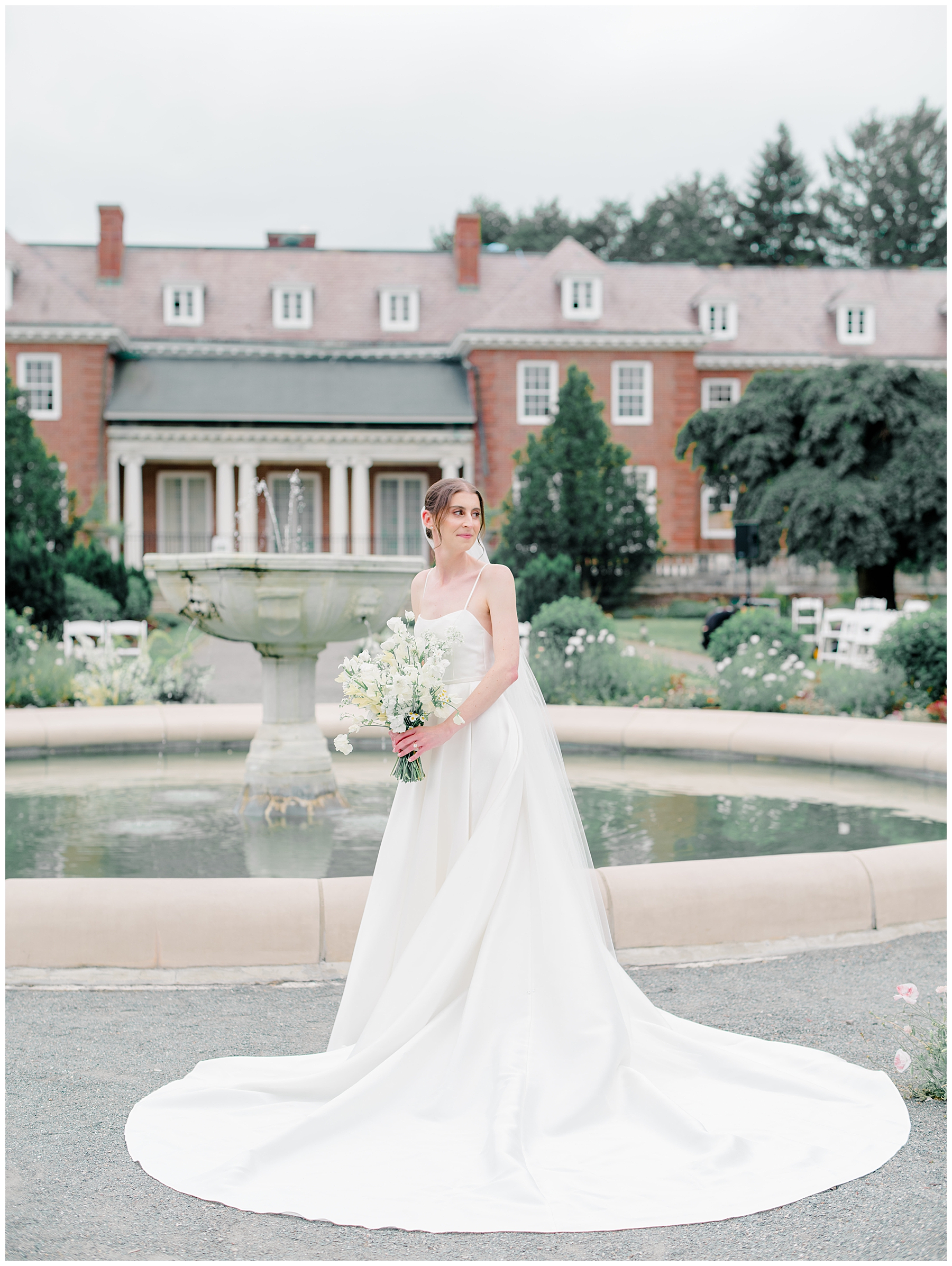 bride stands by fountain at The Gardens at Elm Bank  