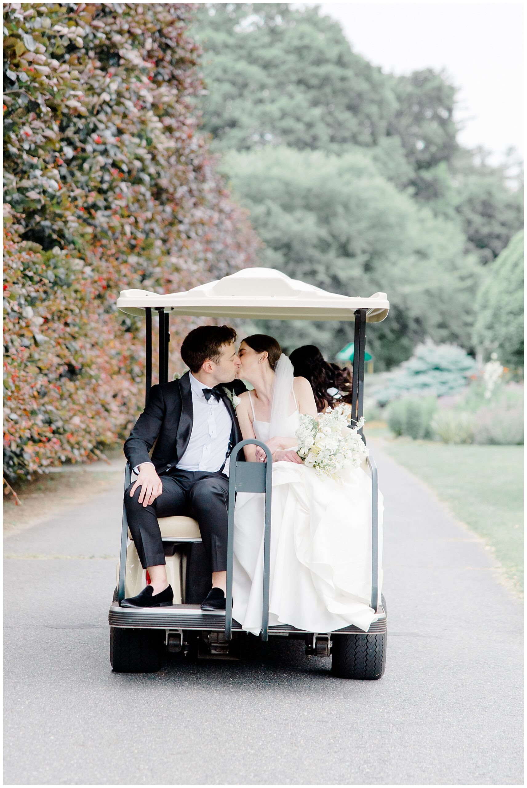 bride and groom kiss as they sit on golf cart