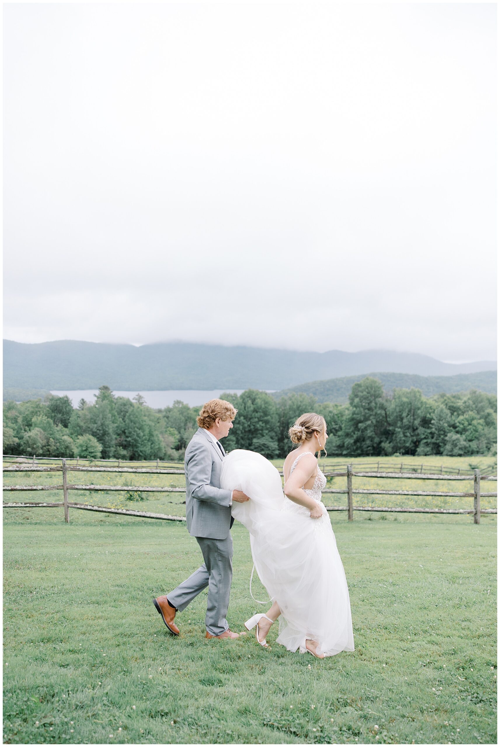 dad helps bride carry back of wedding dress