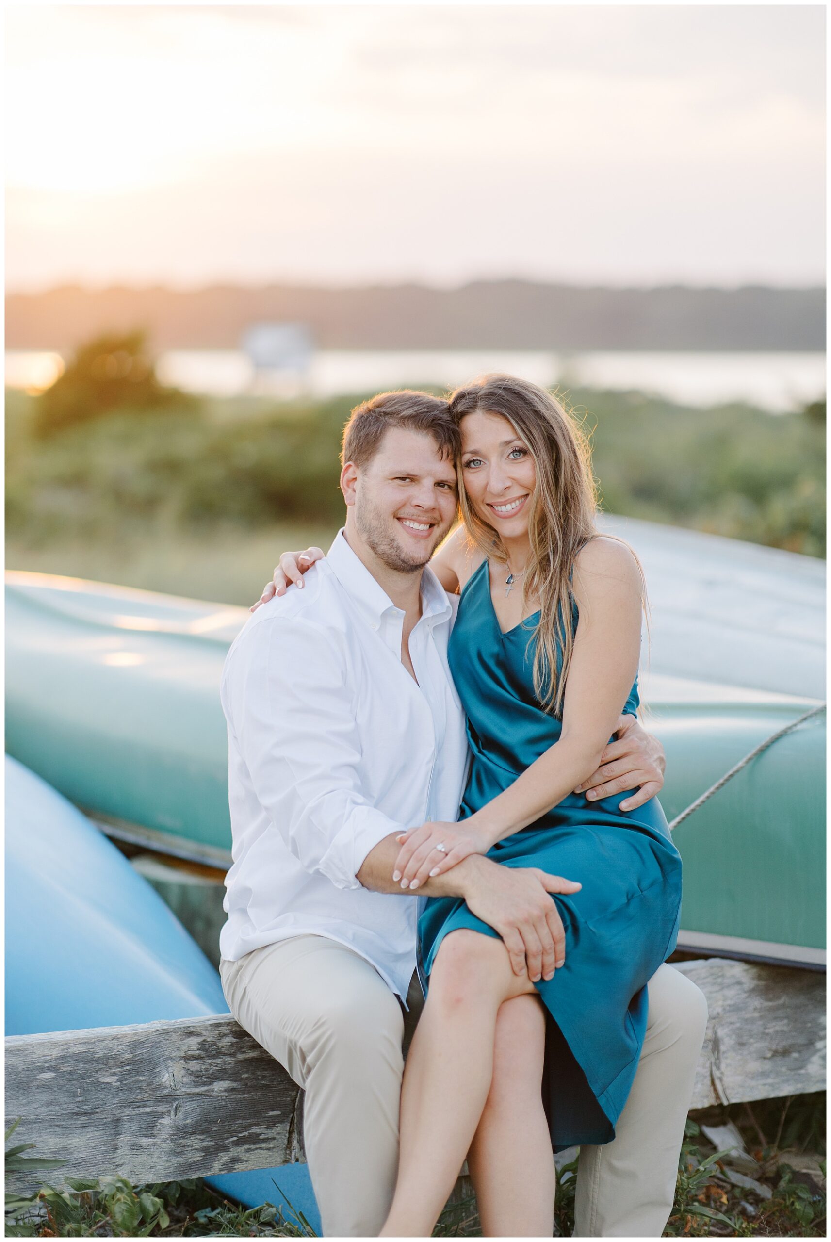 engaged couple sit by canoes
