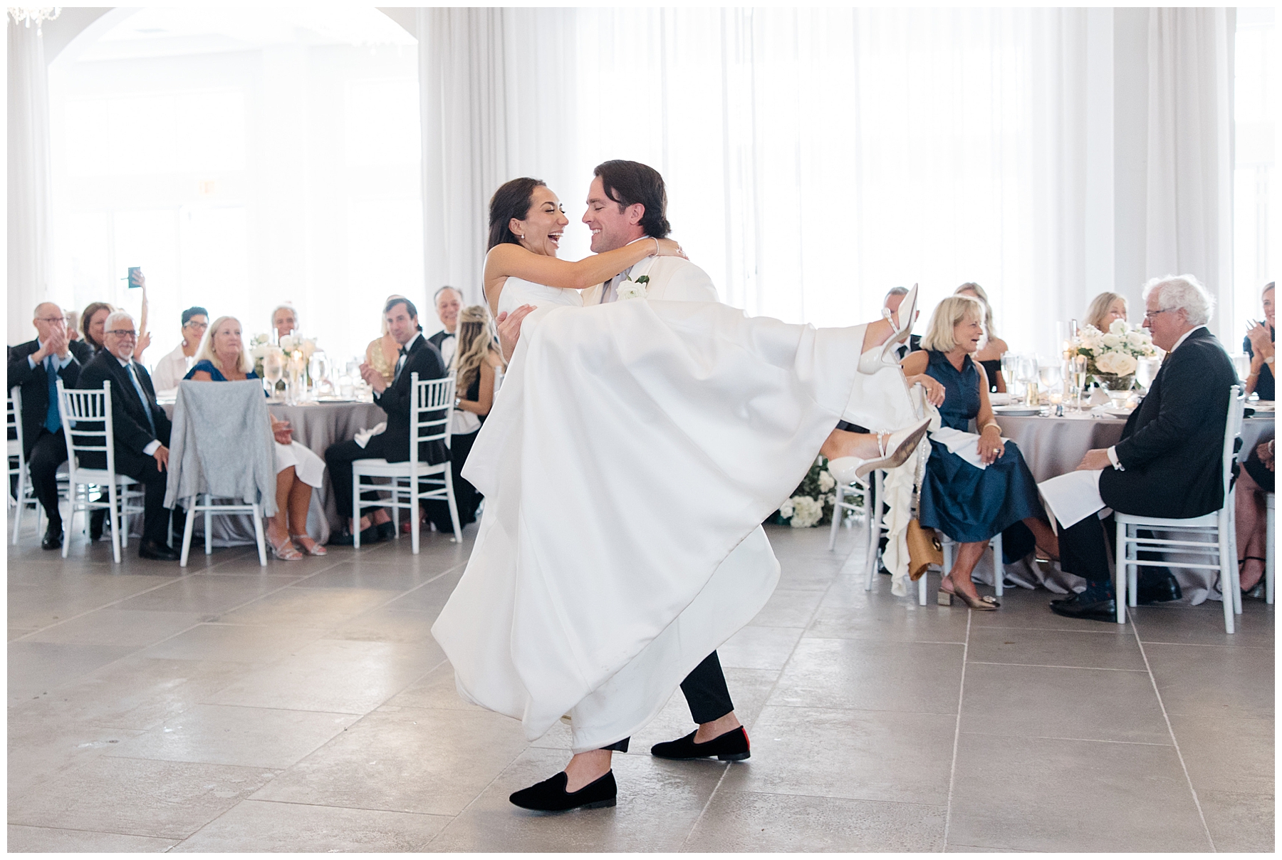 groom holds bride in his arms on the dance floor
