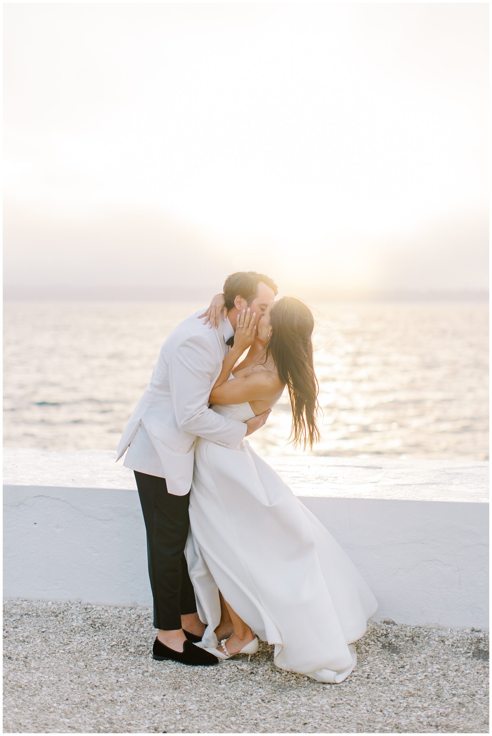 newlyweds kiss during sunset by the water in Newport, RI from Coastal Wedding at Belle Mer