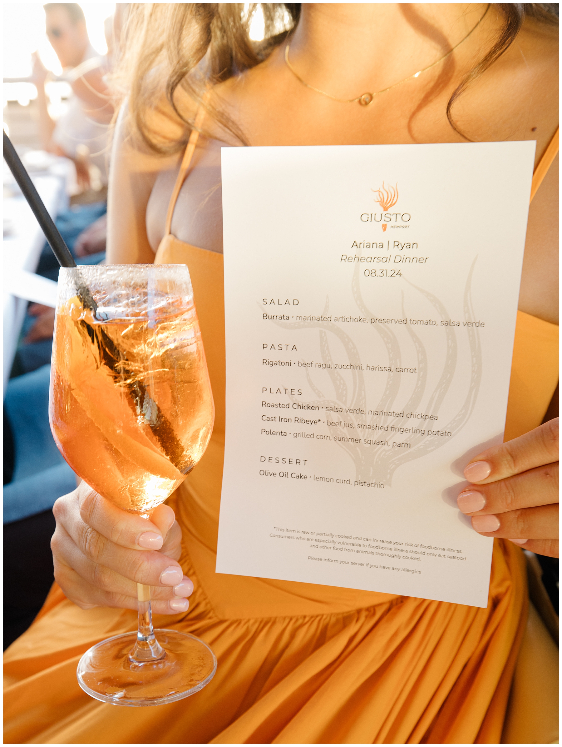Woman in orange dress holds menu and drink