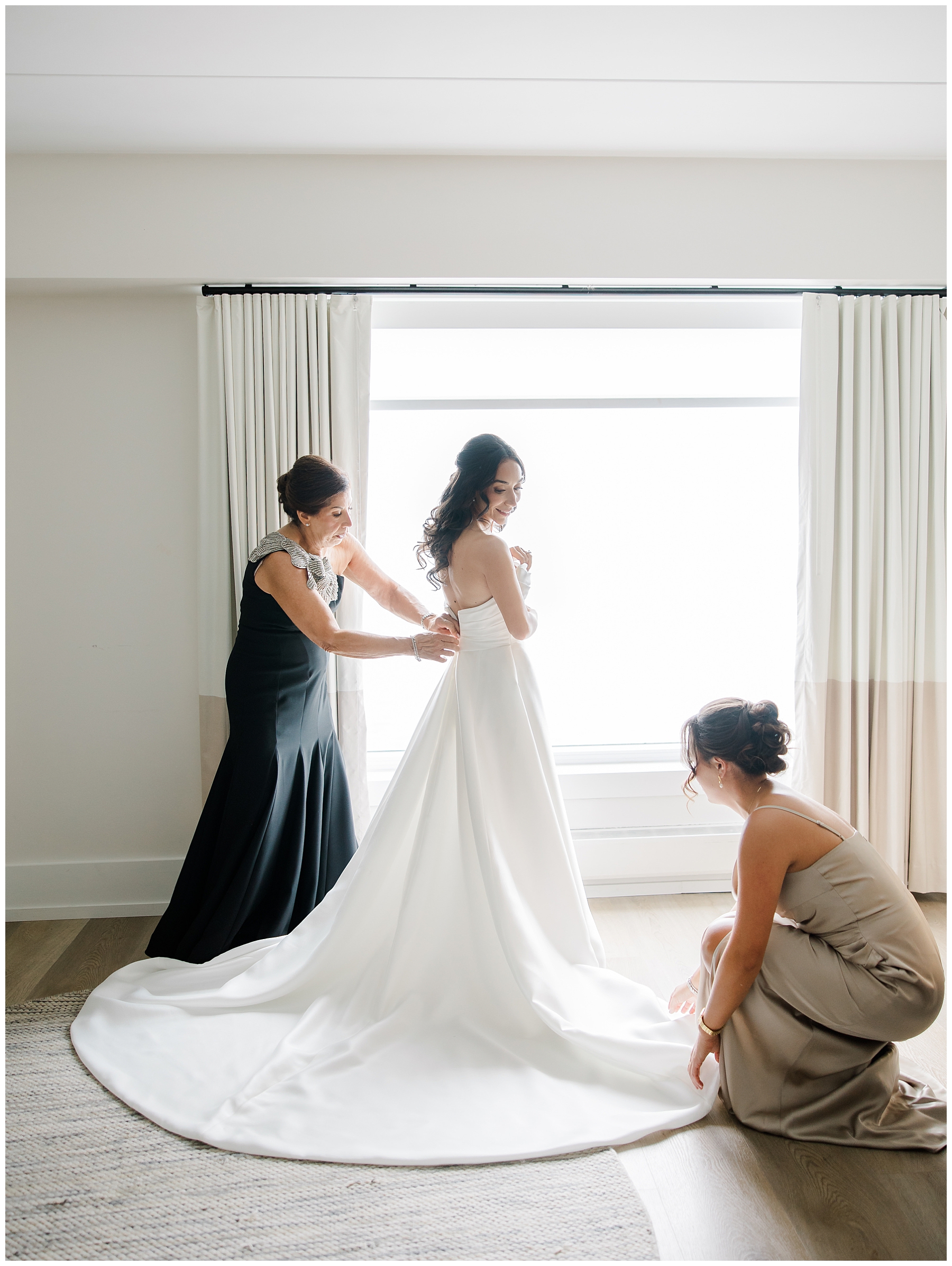 bridesmaids help bride with wedding dress