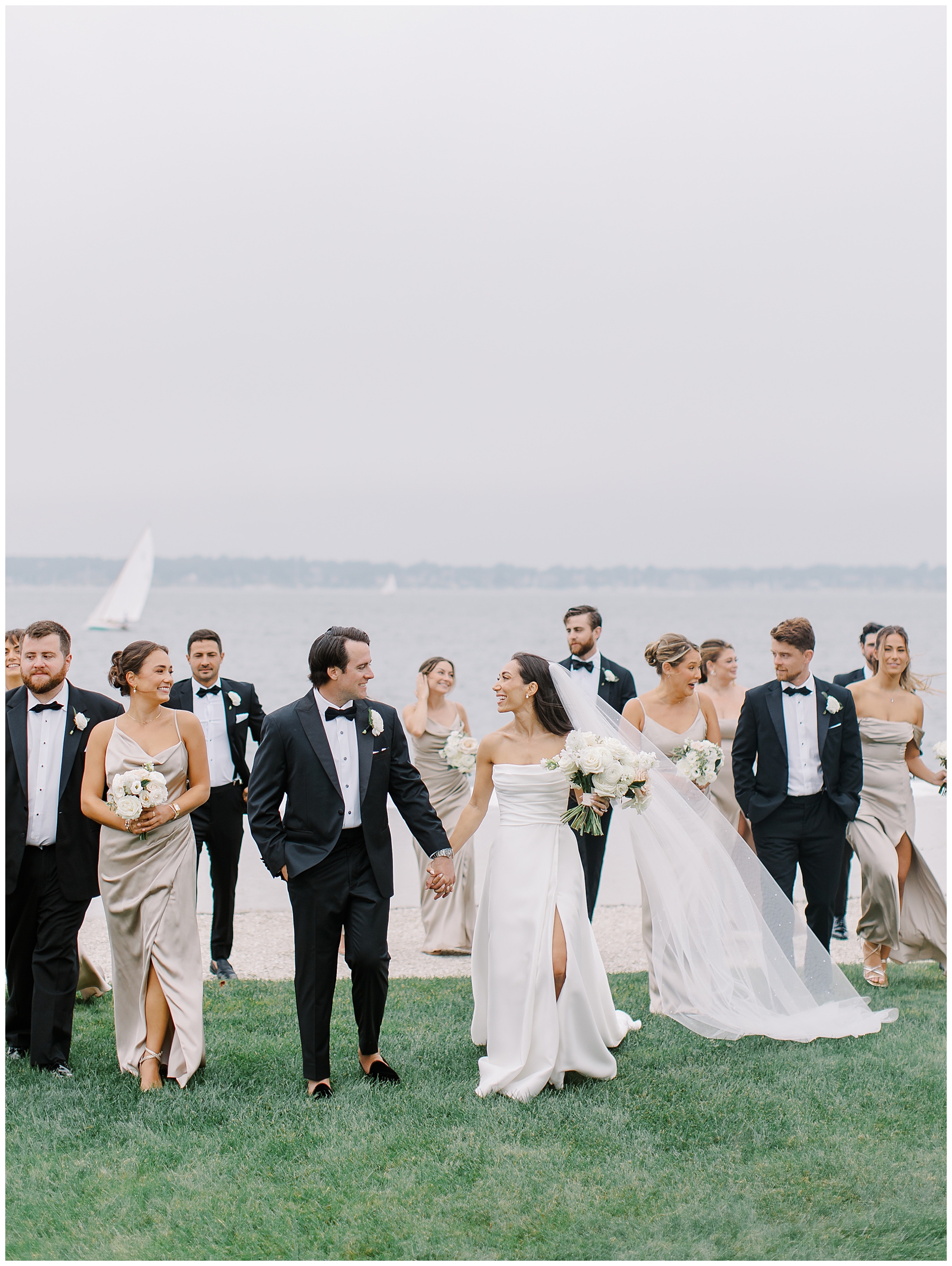 bride and groom hold hands while wedding party surrounds them