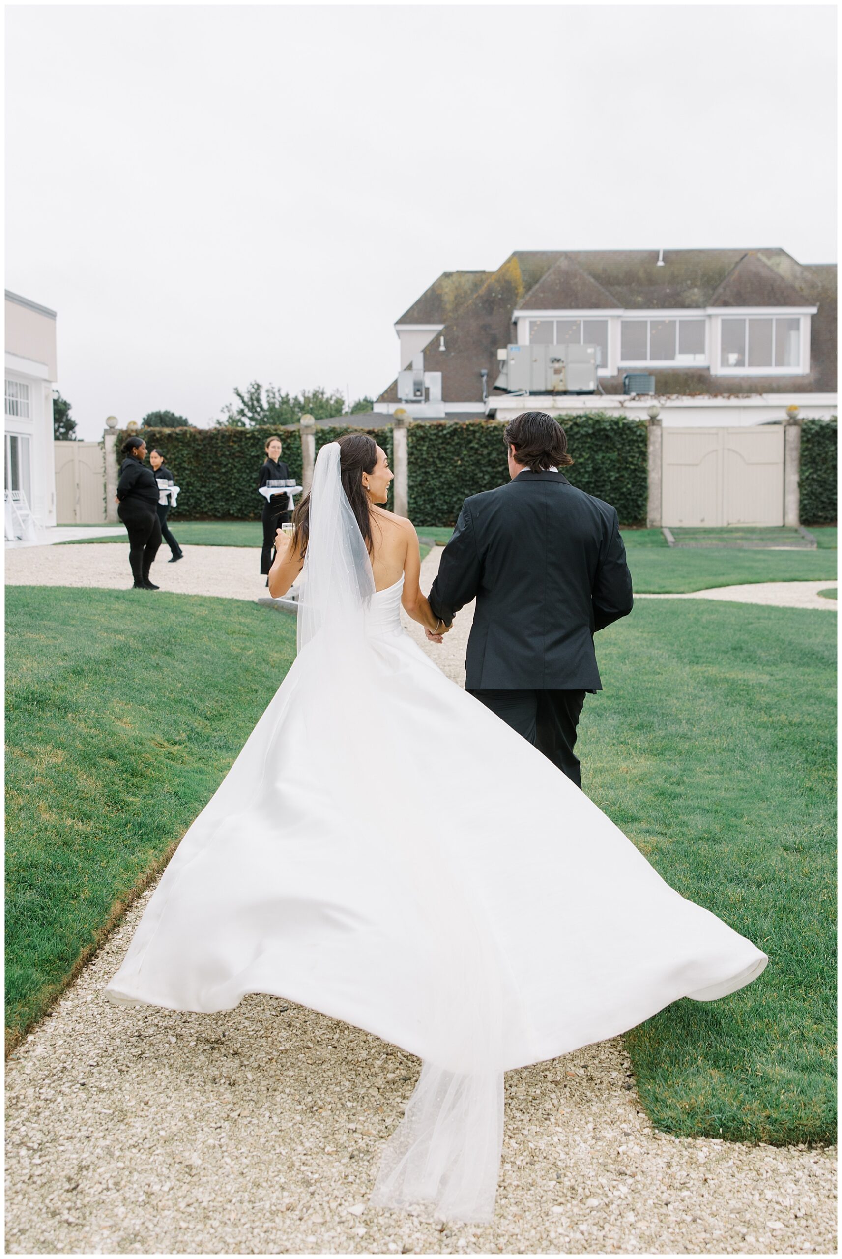 Newlyweds waling away as bride's dress flows behind her