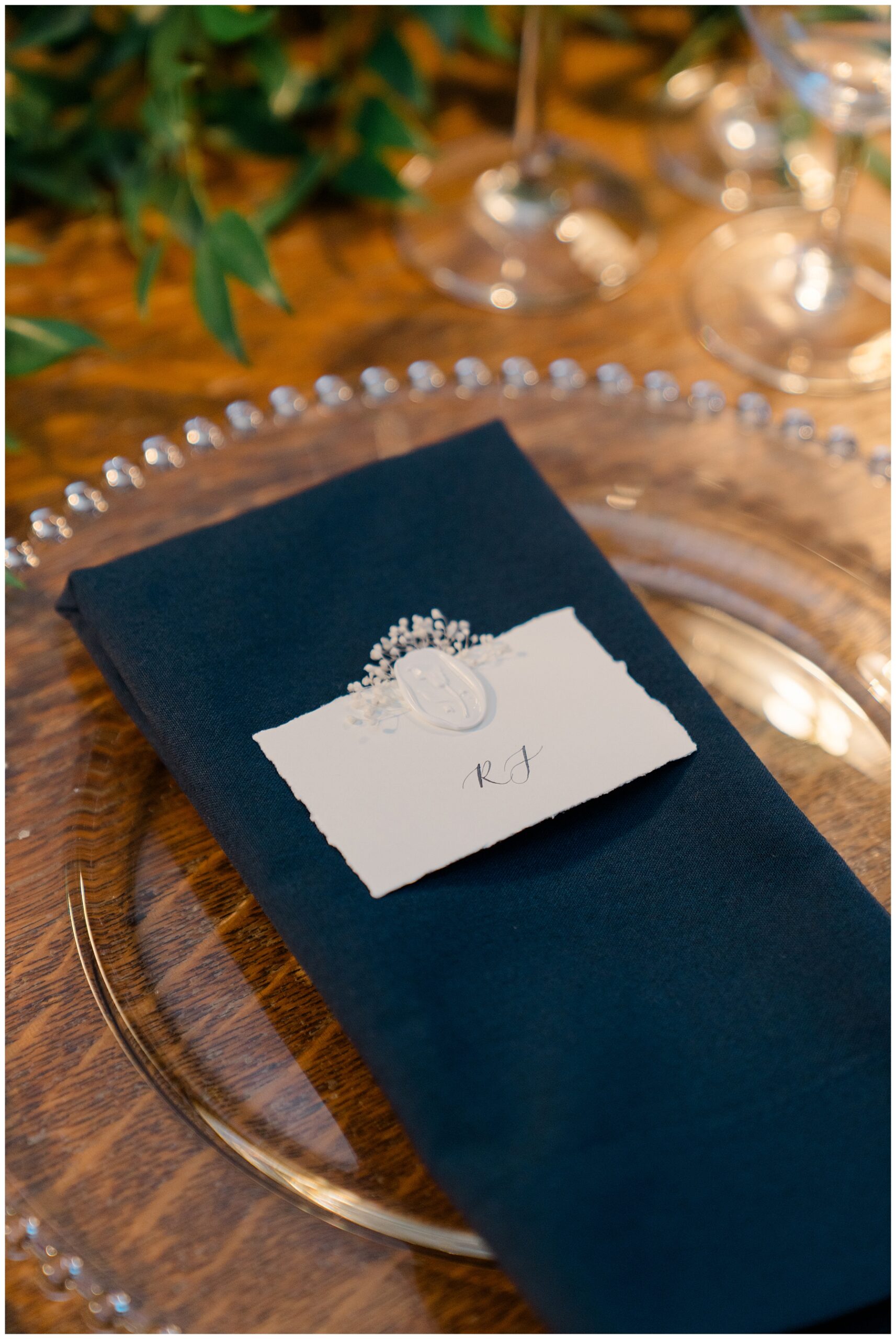 navy napkin on clear plates with white place card