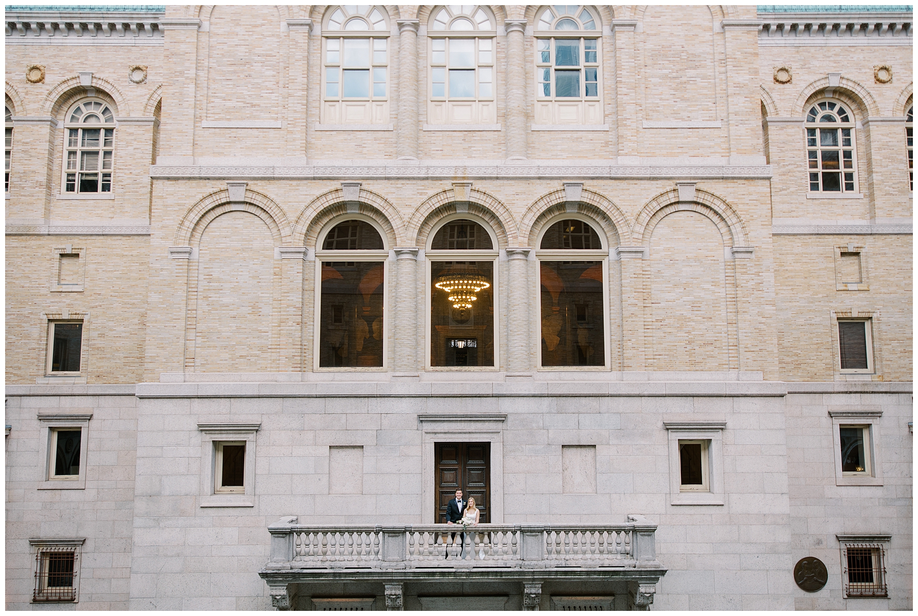 newlyweds on balcony of Boston Public Library overlooking the courtyard