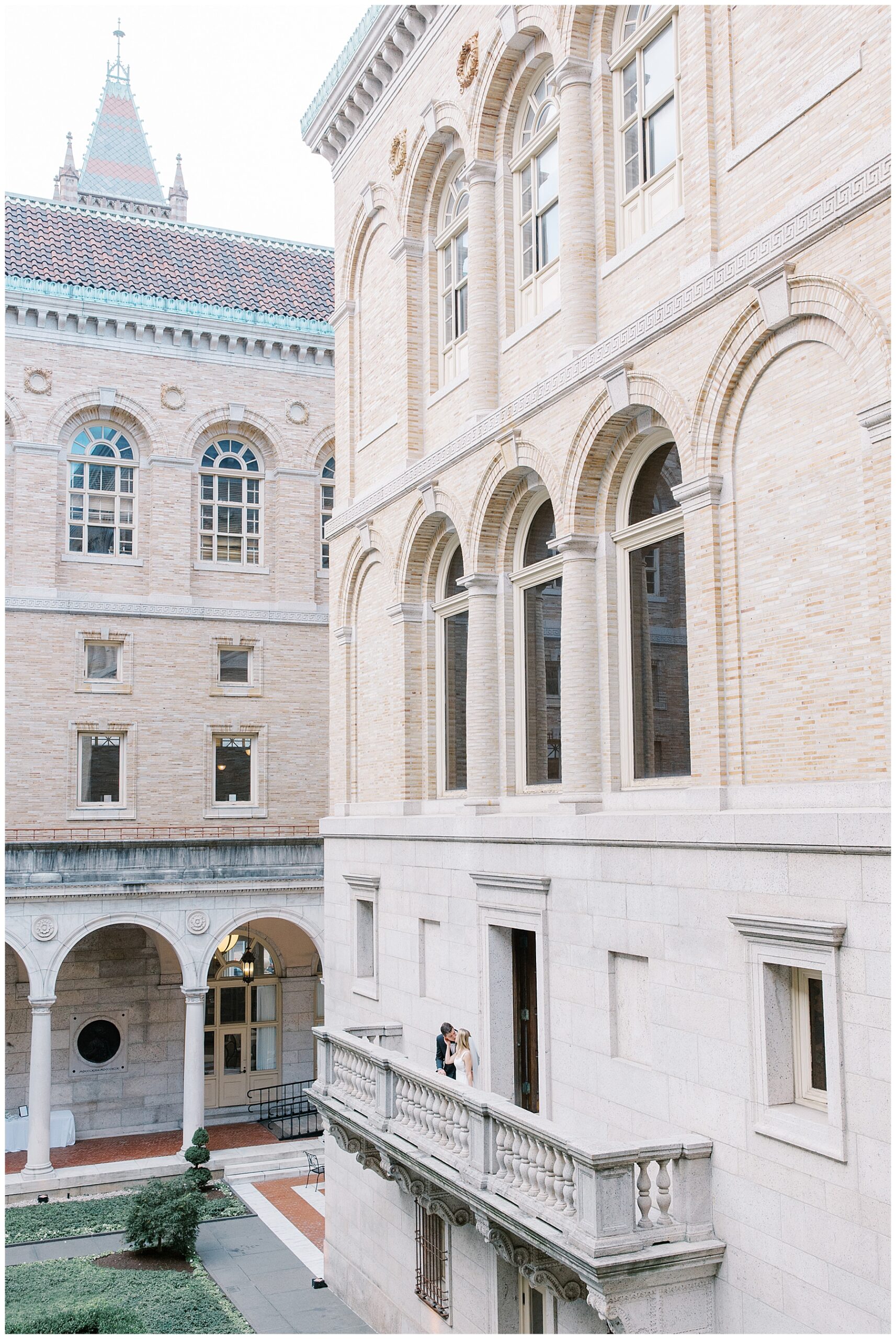 newlyweds on balcony of Boston Public Library overlooking the courtyard