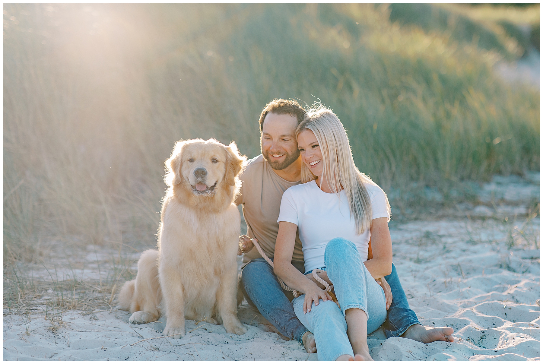 couple sit with their dog on the beach