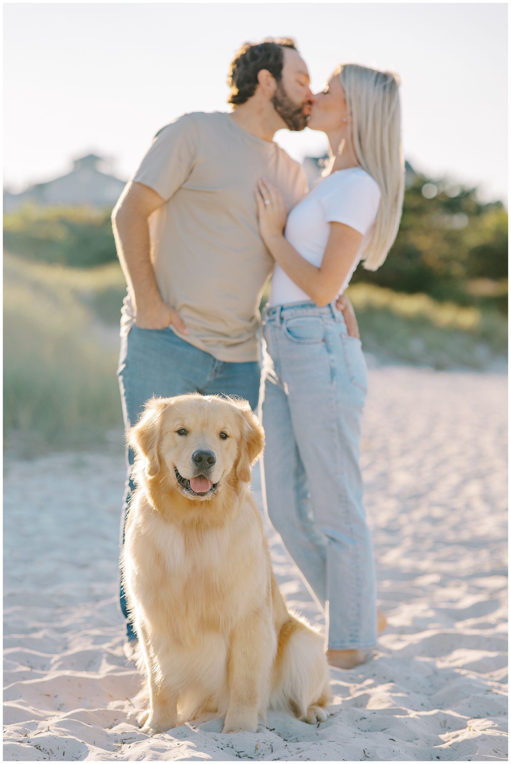 couple kiss with dog sitting in front of them