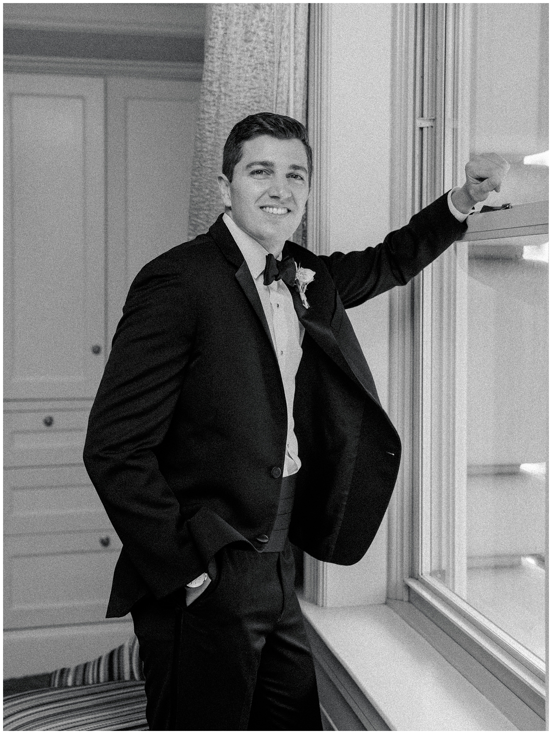 groom leans on window ledge