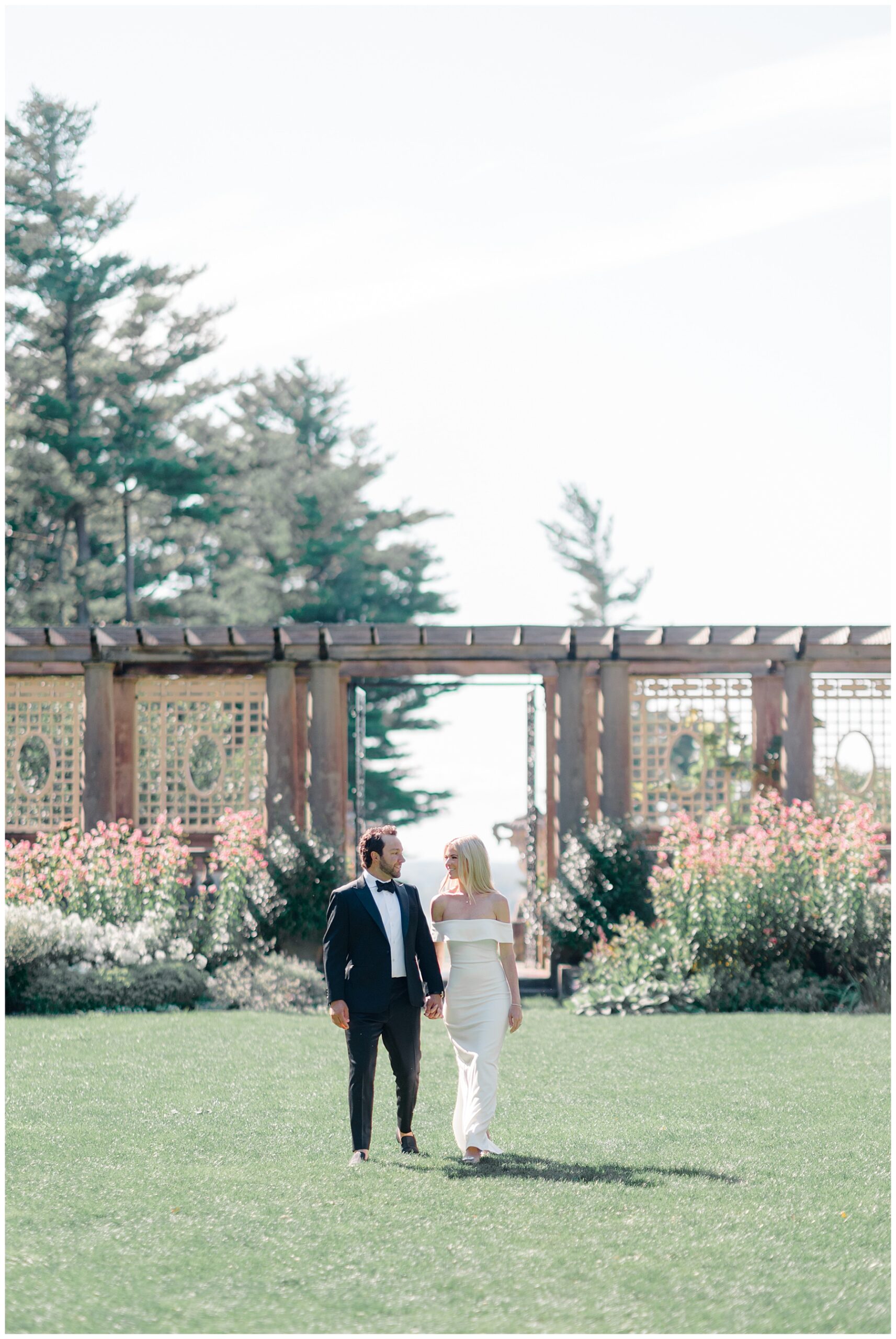 romantic engagement photo of couple walking across lawn of estate