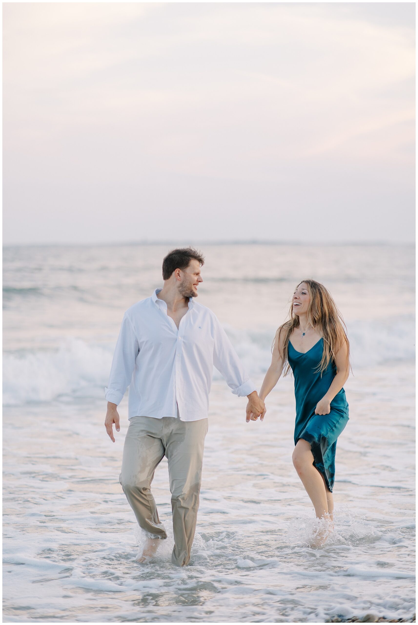candid beach engagement photos of couple walking in the water