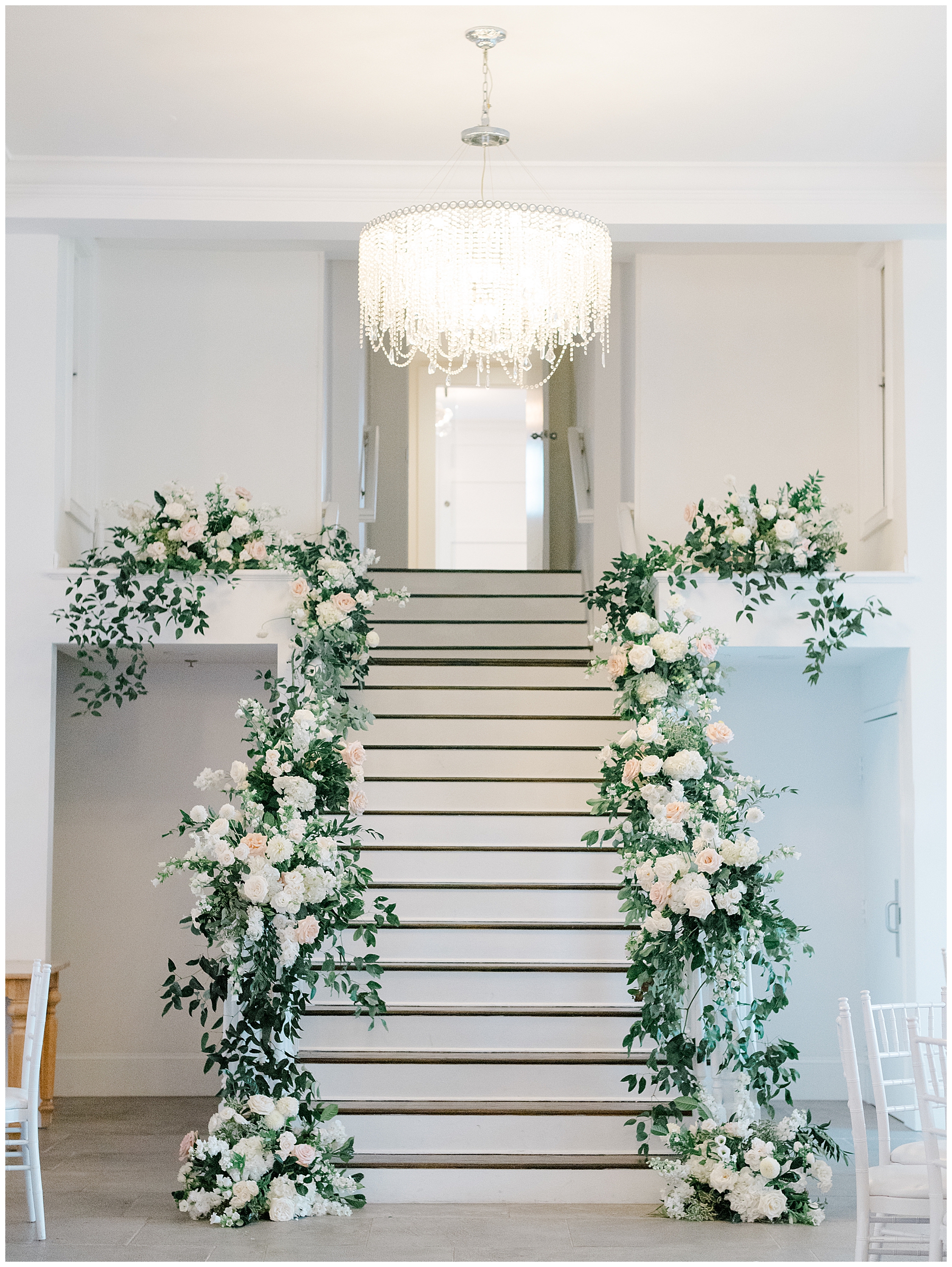 white flowers and greenery decorate staircase from Coastal Wedding reception at Belle Mer, A Longwood Venue in Newport