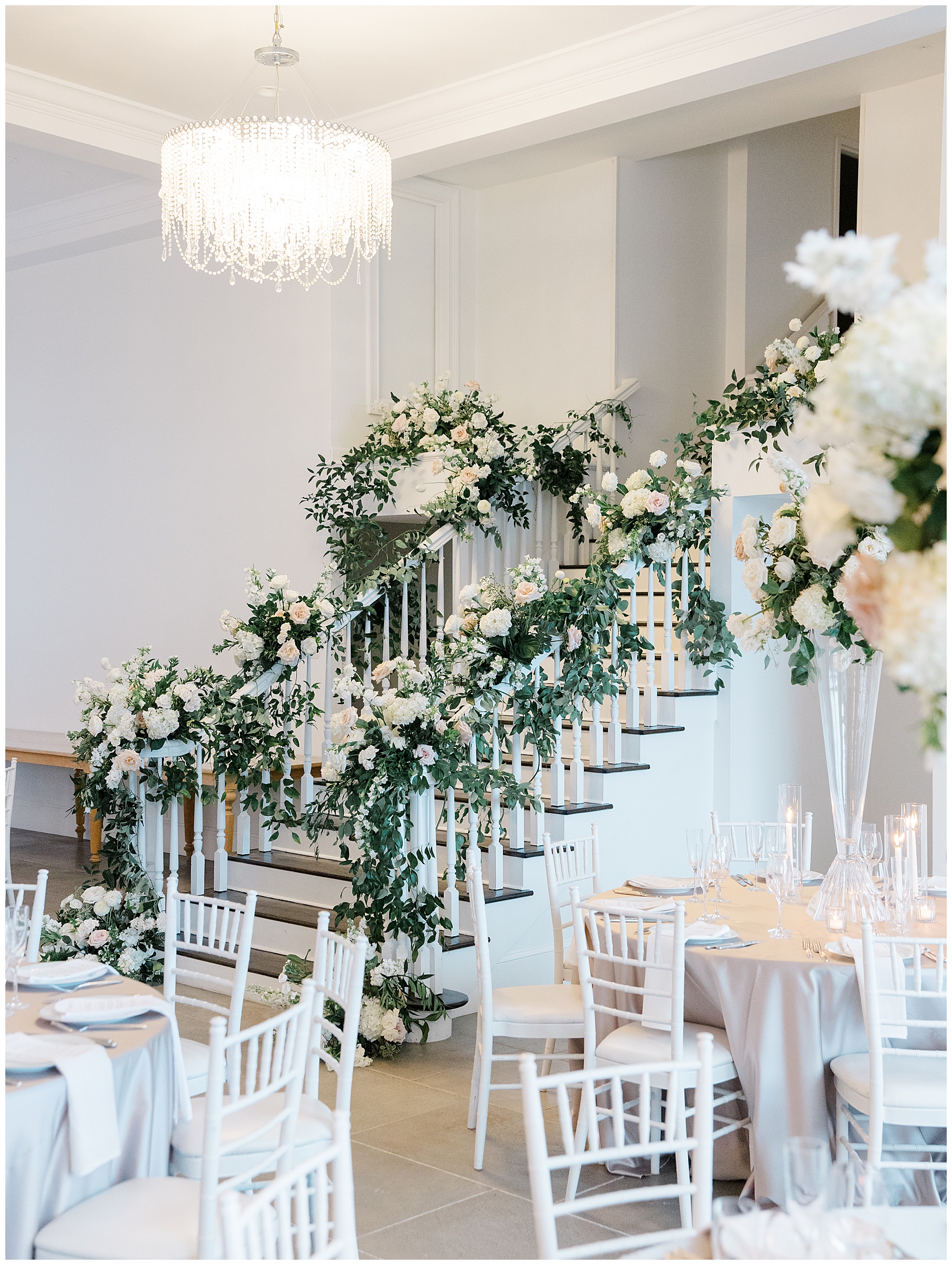white flowers and greenery decorate staircase from Coastal Wedding reception at Belle Mer, A Longwood Venue in Newport