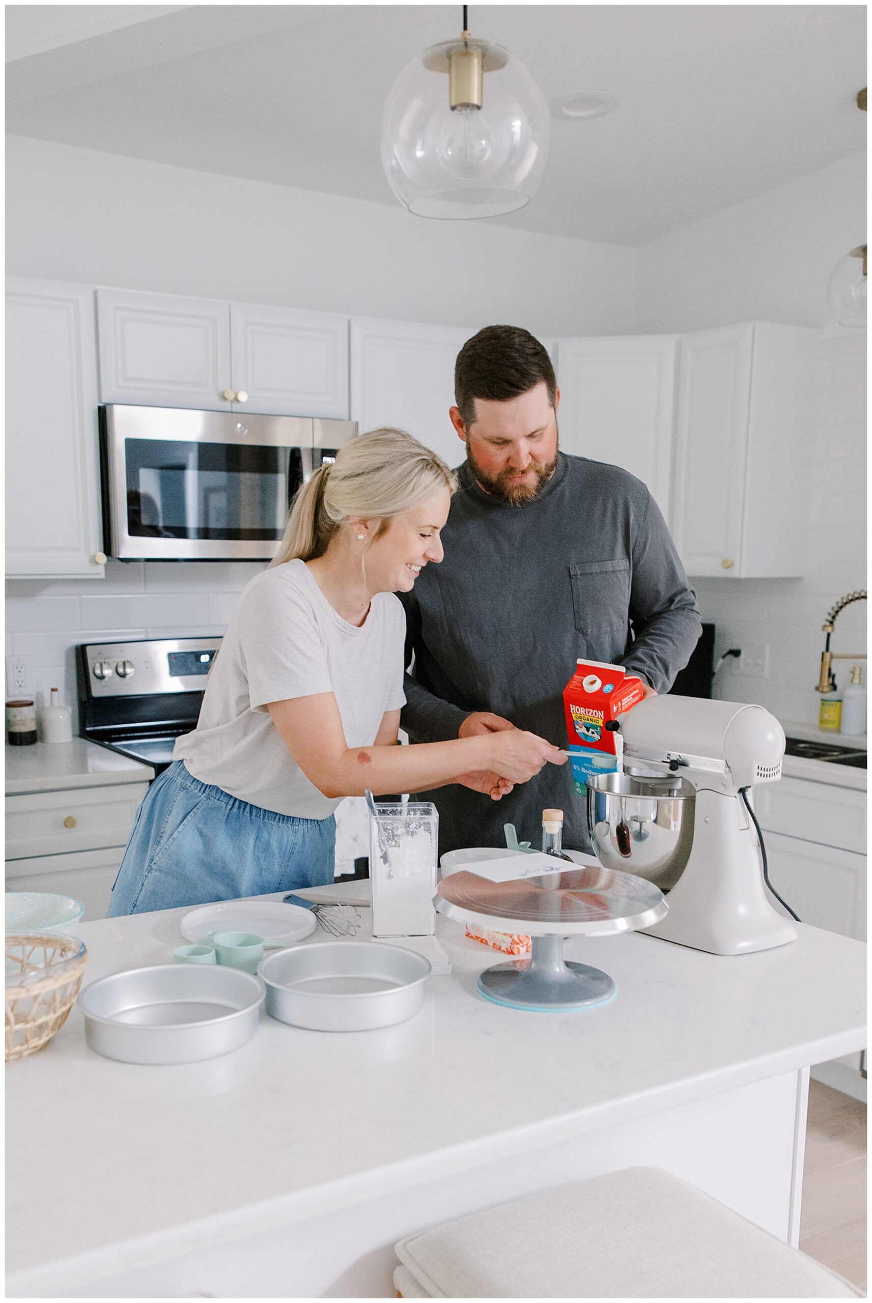 engaged couple baking wedding cake together during Candid At-Home Engagement Photoshoot
