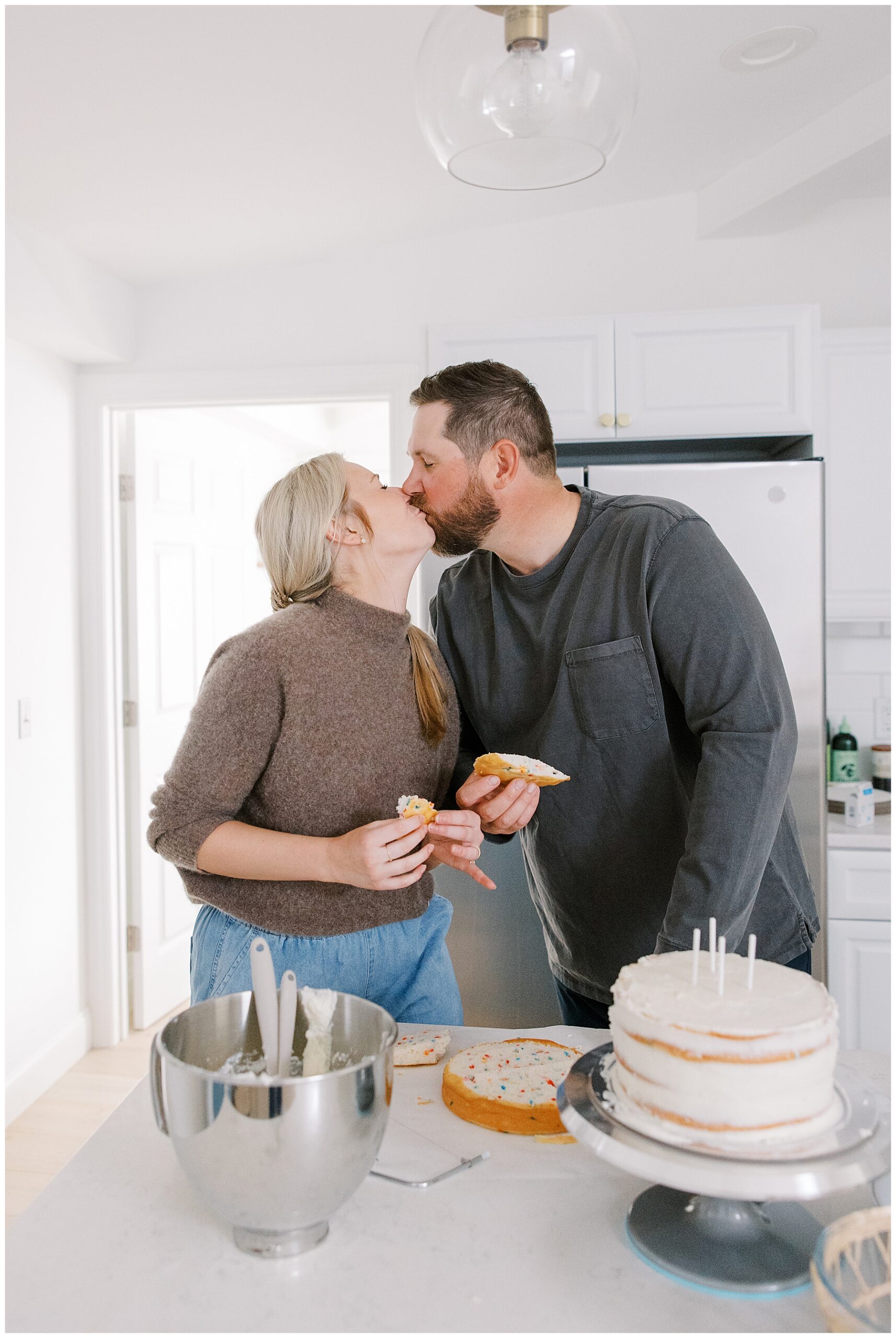 couple kiss in kitchen while icing cake