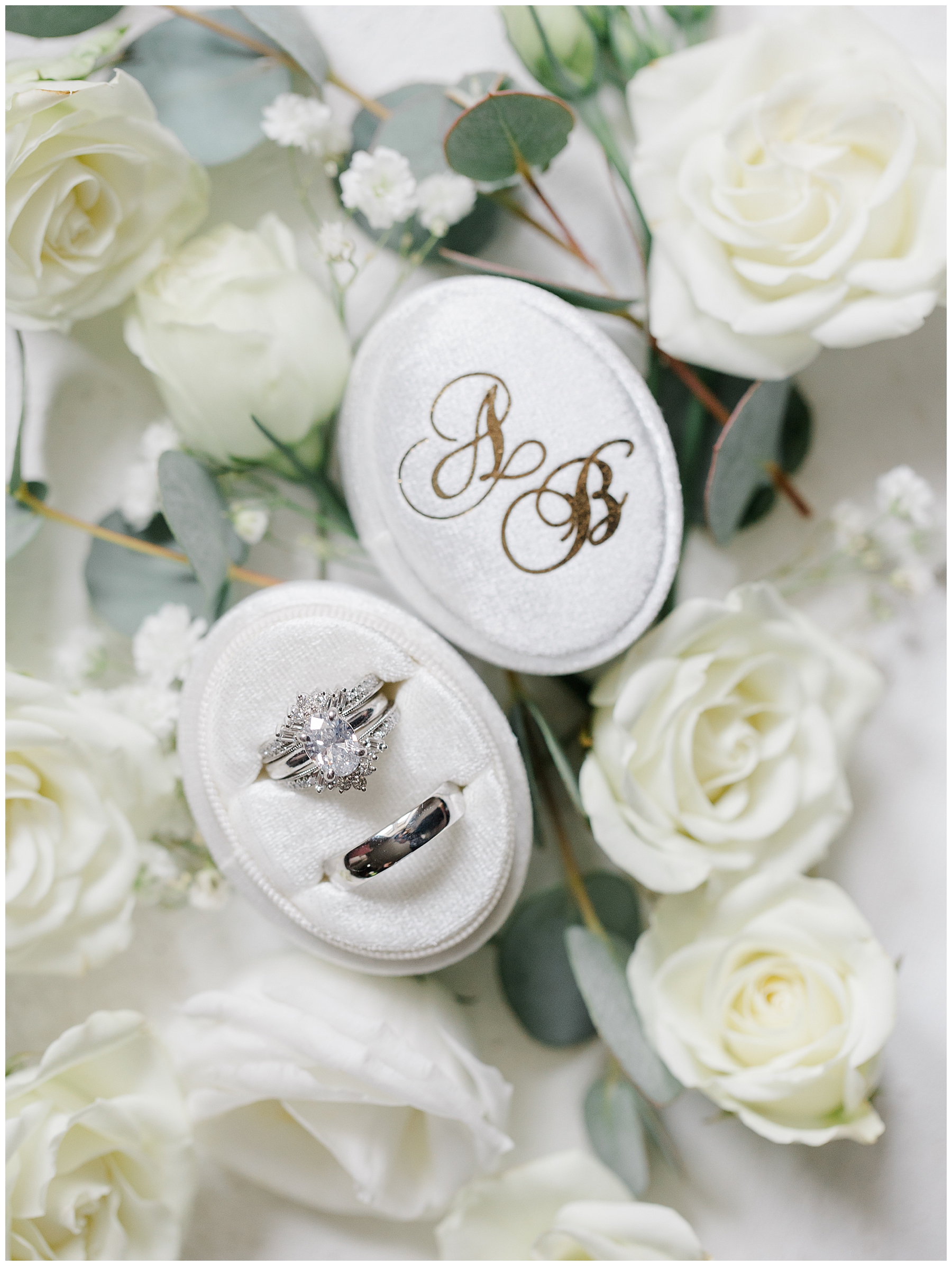 wedding rings in white ring box surrounded by white roses